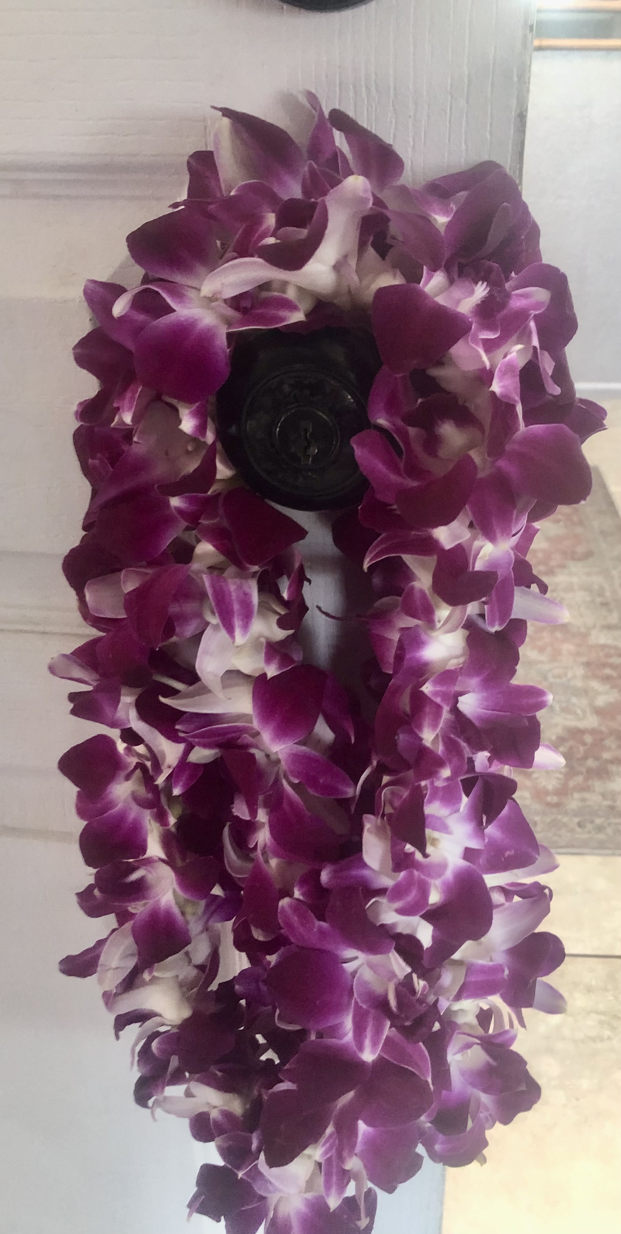 Purple orchid lei draped over a dark doorknob