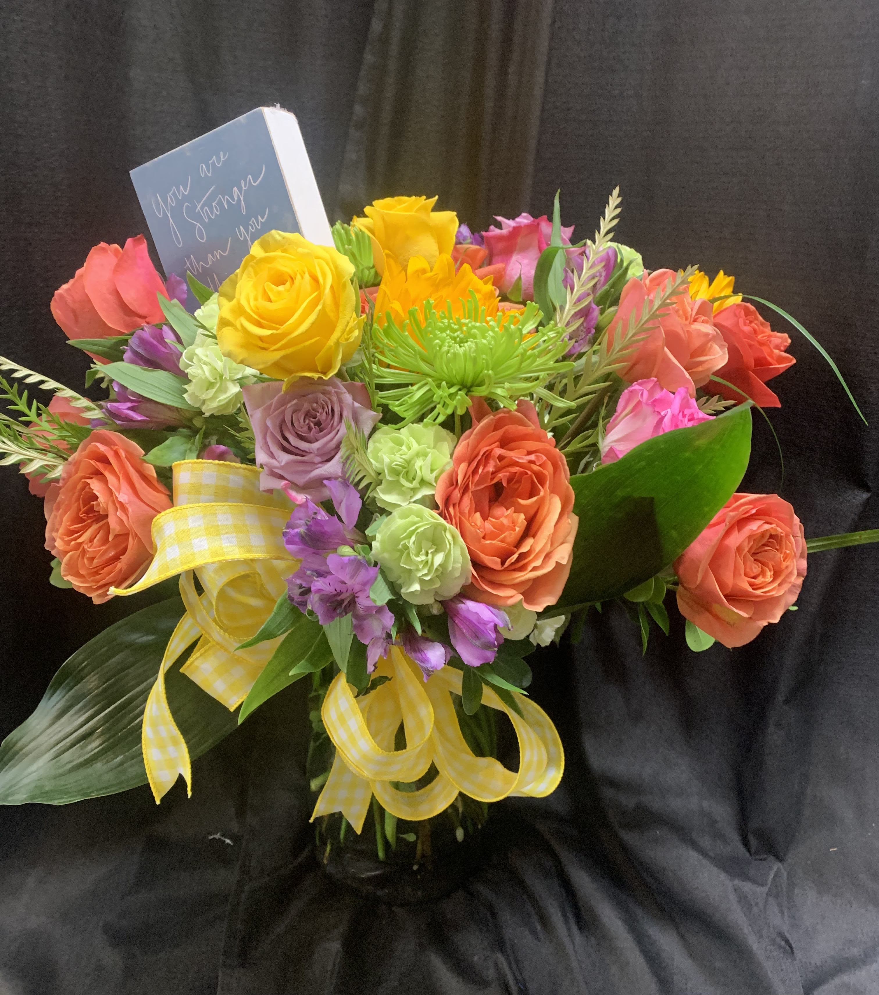 Colorful bouquet of roses and mixed flowers with a yellow ribbon in a vase