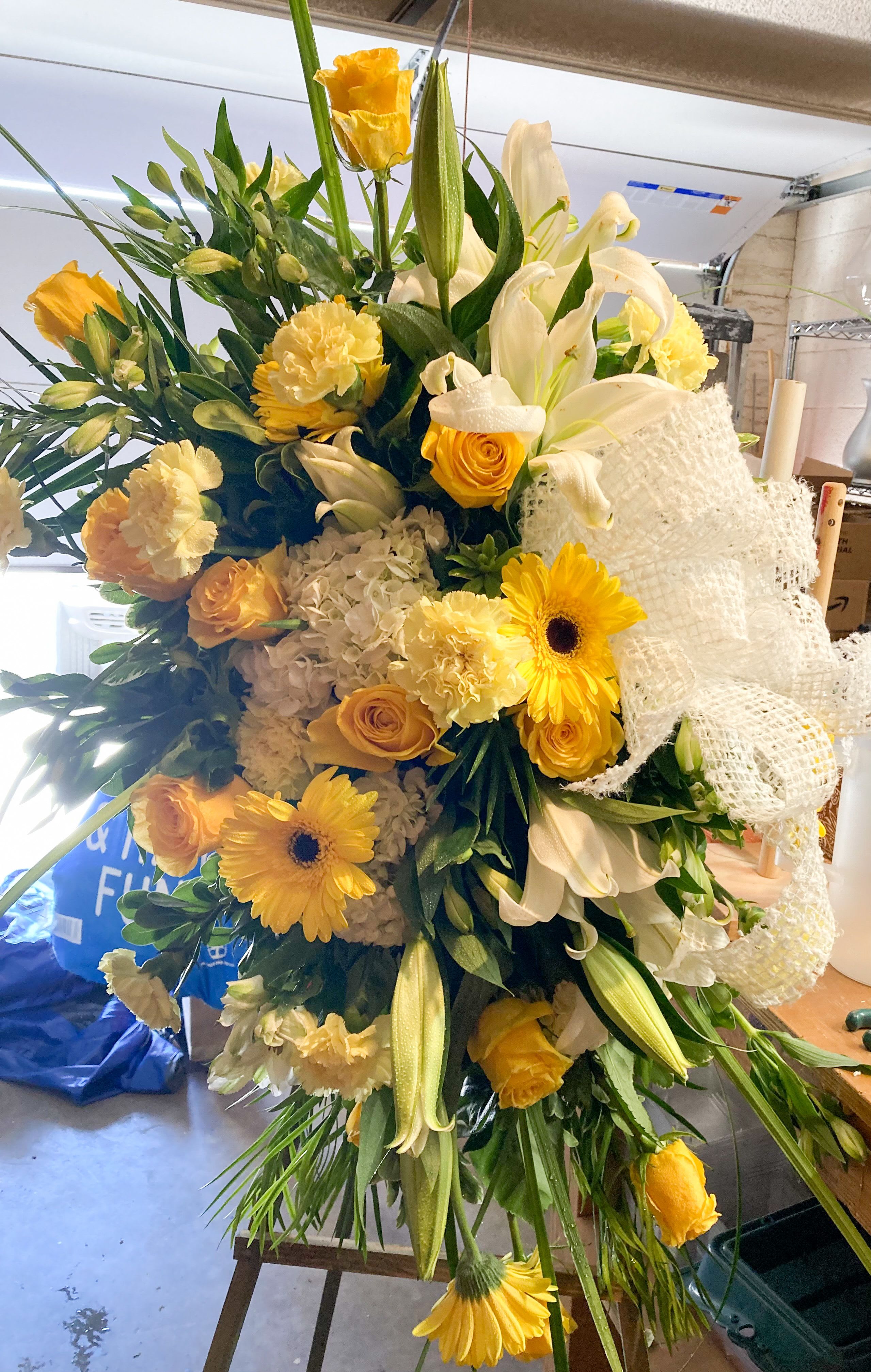 Large bouquet of yellow and white flowers with a white mesh ribbon