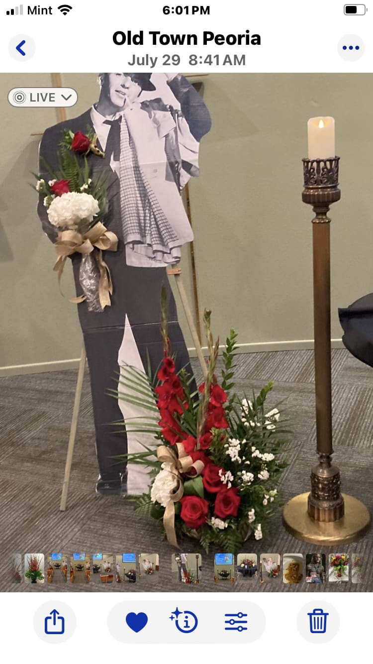 Red and white floral spray beside a cardboard cutout and candle