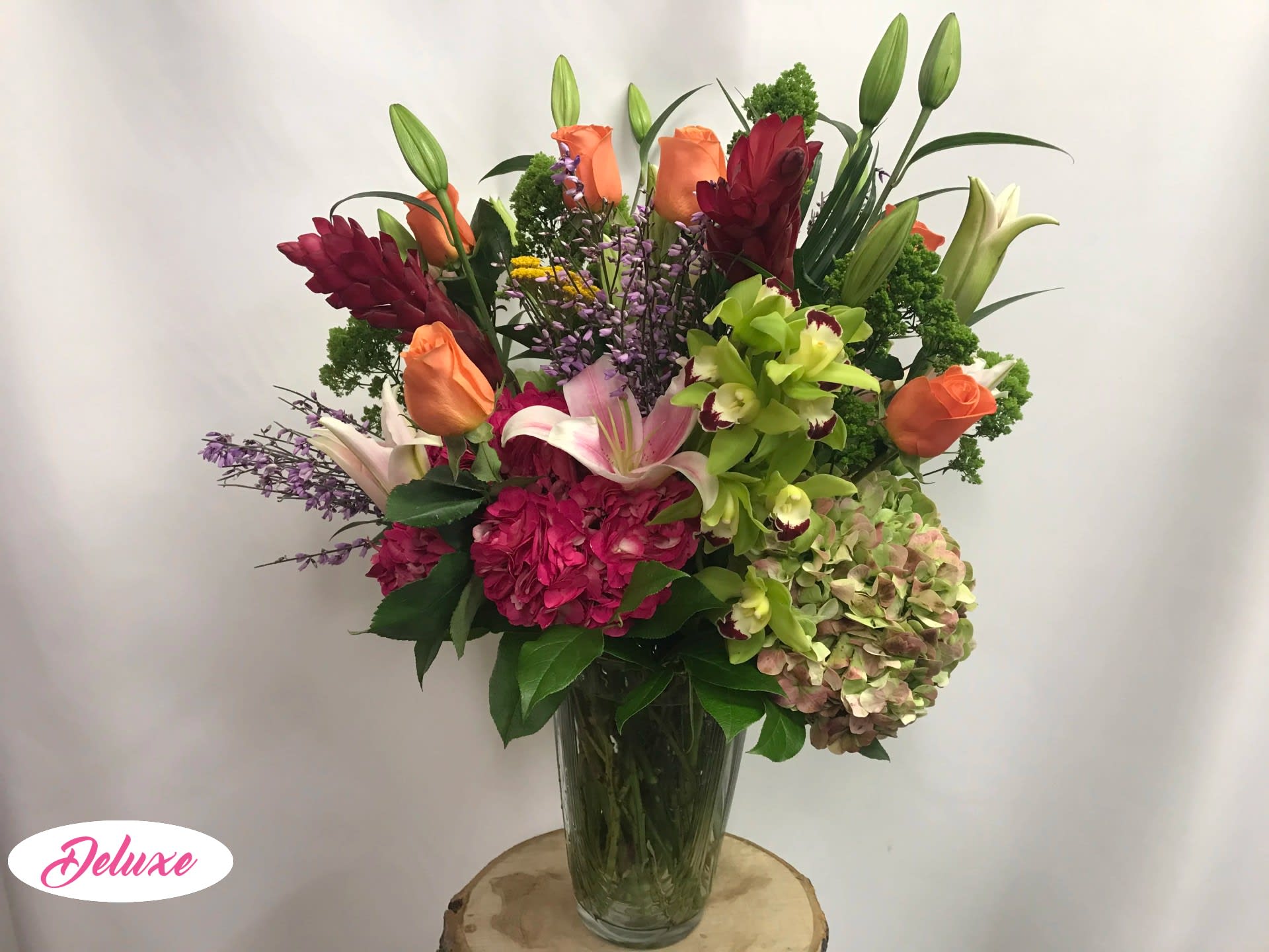Mixed bouquet of lilies, roses, orchids, and hydrangea in a glass vase