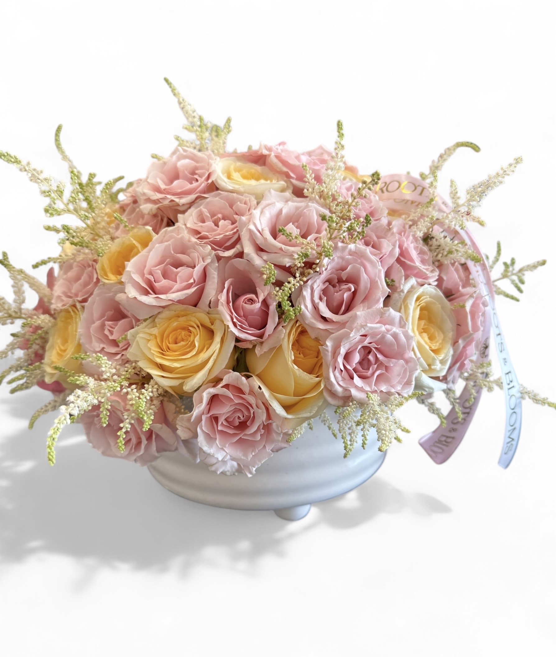 Pink and yellow roses arranged in a white bowl