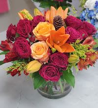 Scream Summer - small clear-vase arrangement of red, magenta and yellow roses with orange accents and greenery