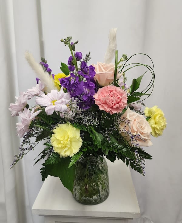 Mixed bouquet in a glass vase with purple, pink, yellow, and white flowers