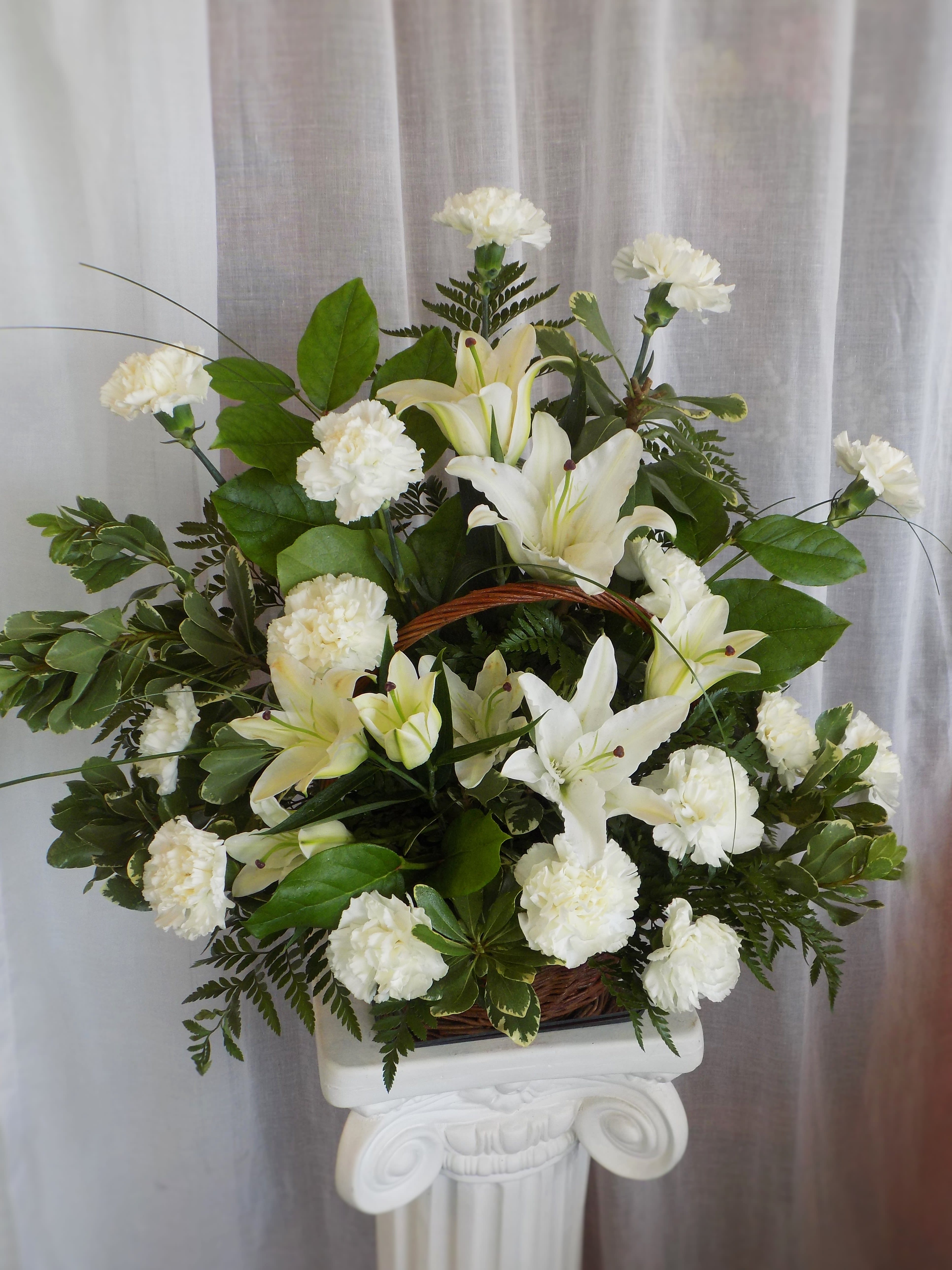 White lilies and carnations in a pedestal arrangement