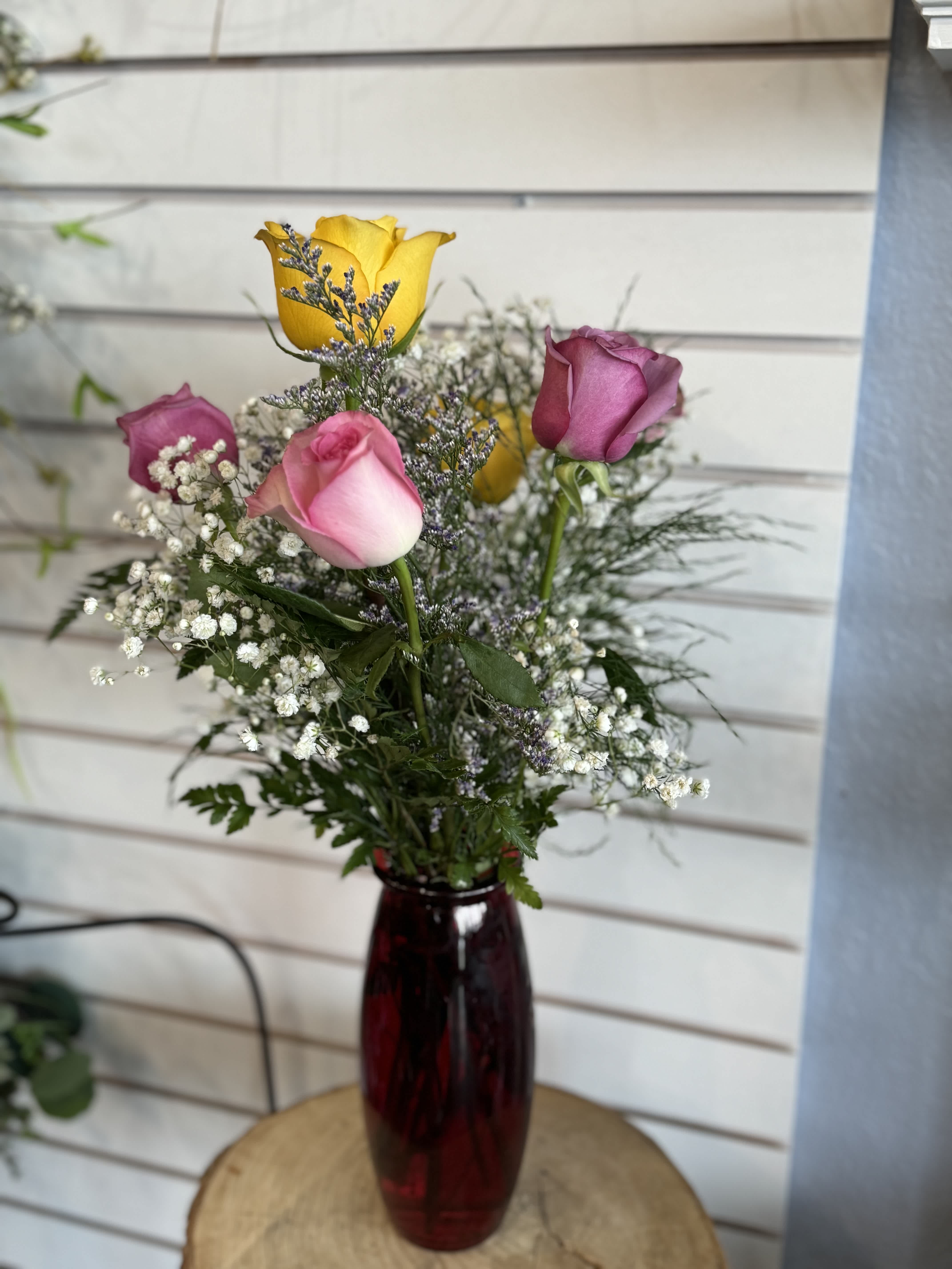 Mixed roses in a red glass vase with baby's breath
