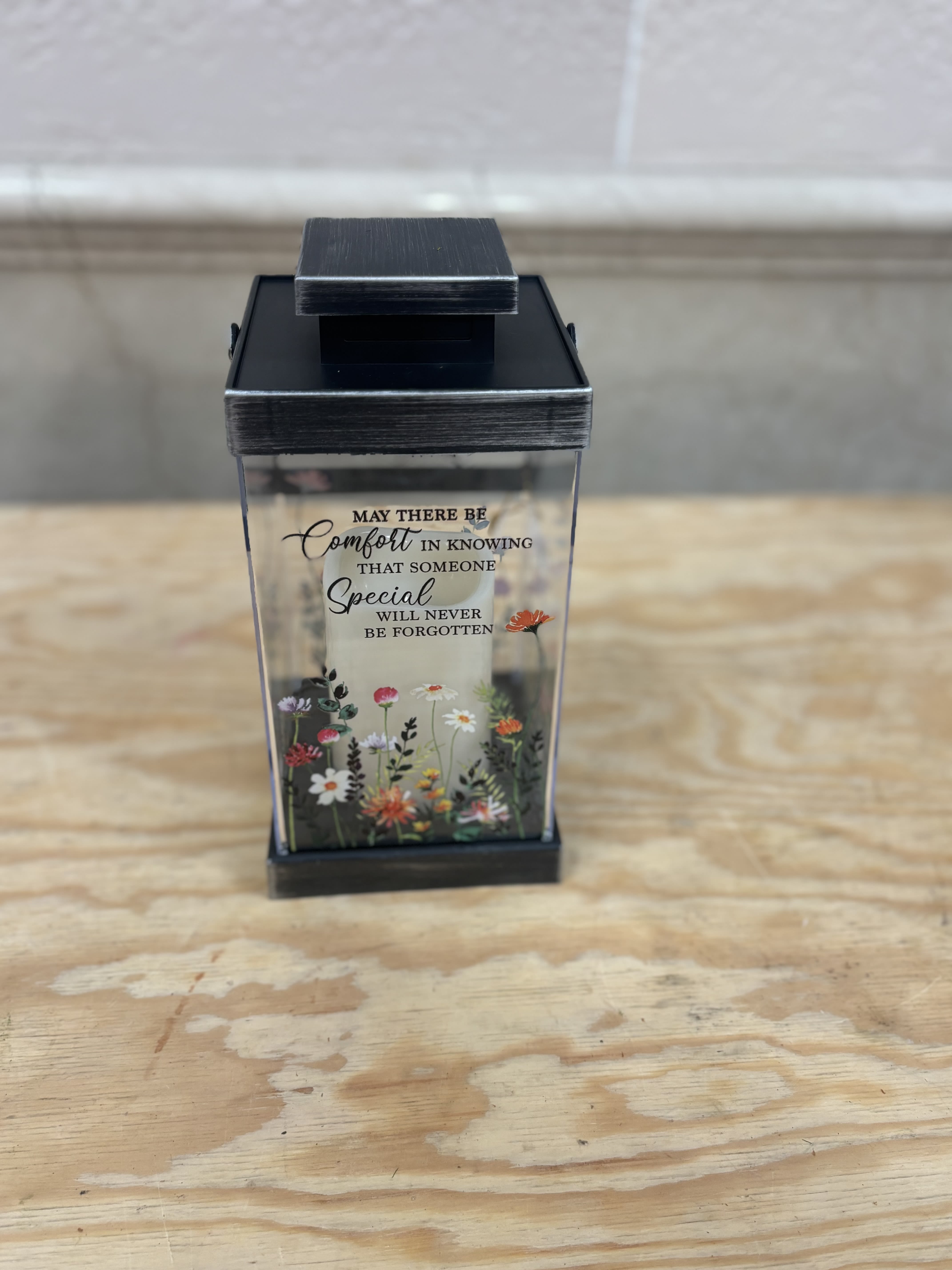 Black memorial lantern with a printed sympathy message and small floral design