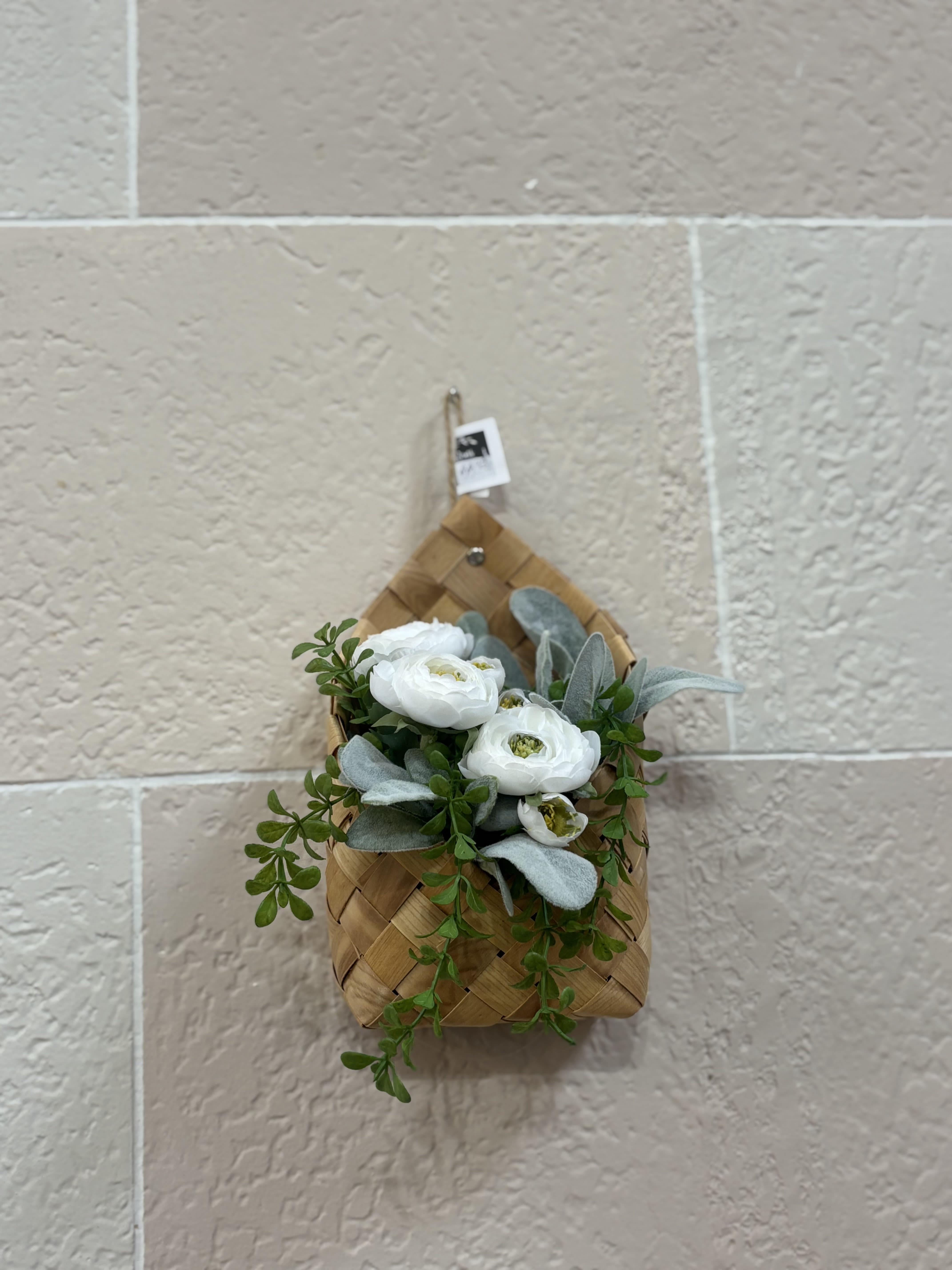 White flowers and greenery in a woven wall basket