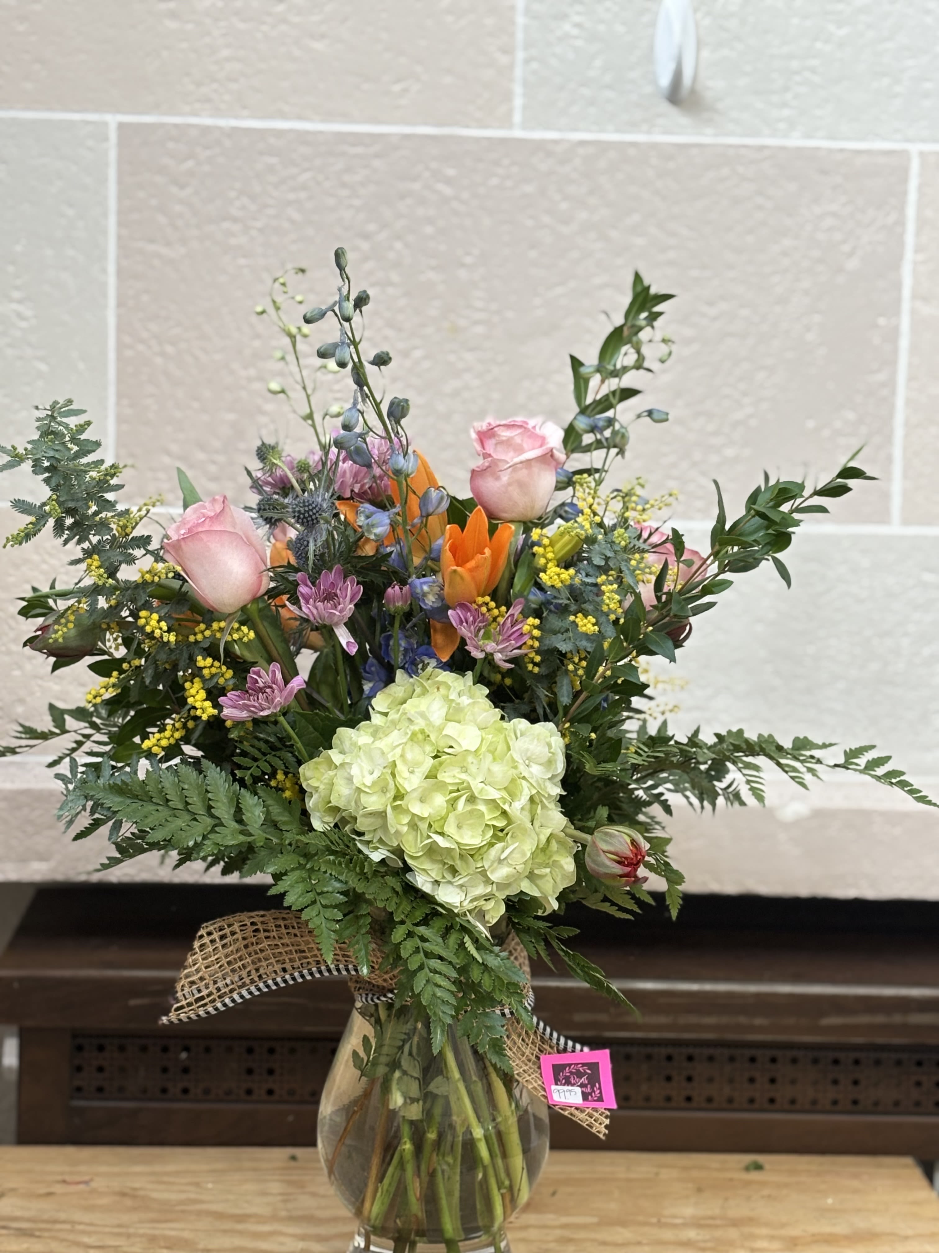 Mixed bouquet in a glass vase with pink roses and a green hydrangea bloom
