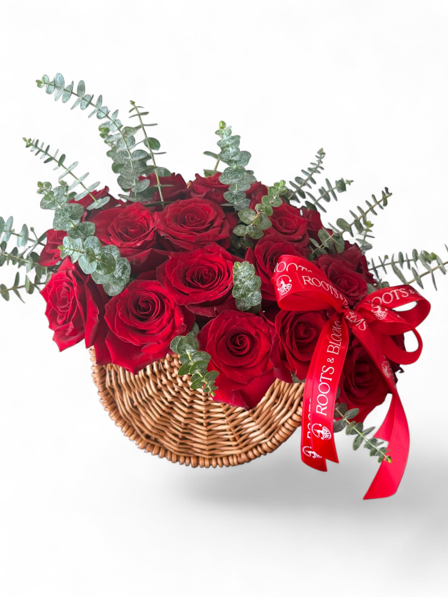 Red roses in a wicker basket with eucalyptus and a red ribbon