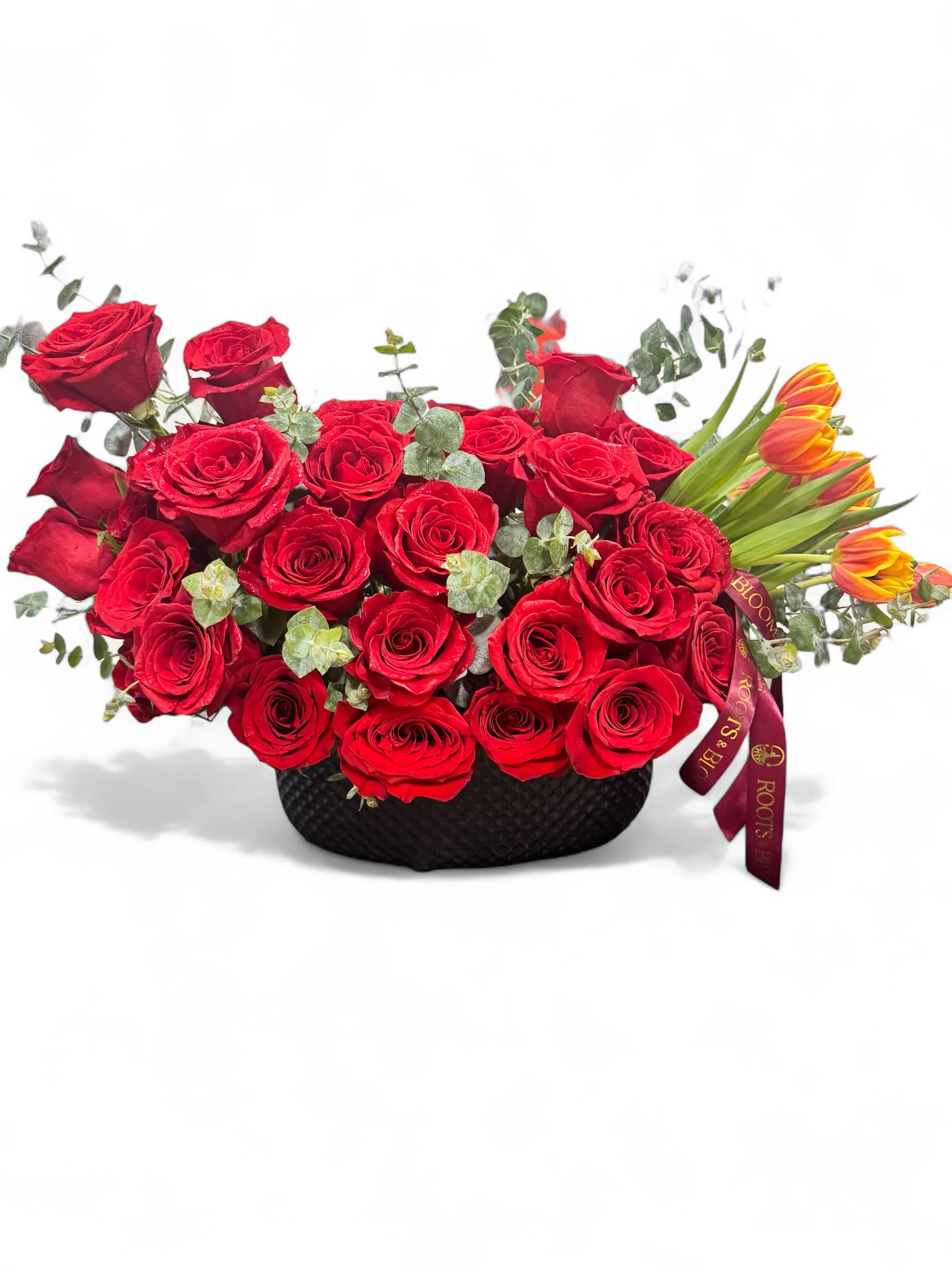 Red roses arranged in a black basket with orange tulips
