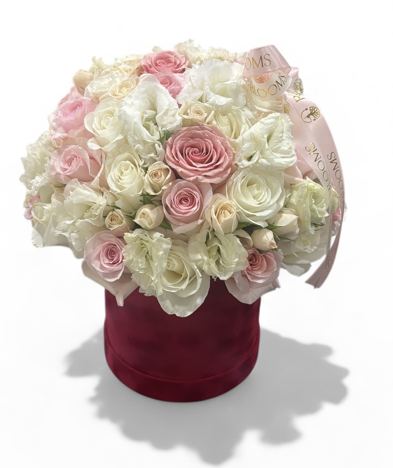 Pink and white roses arranged in a burgundy hatbox