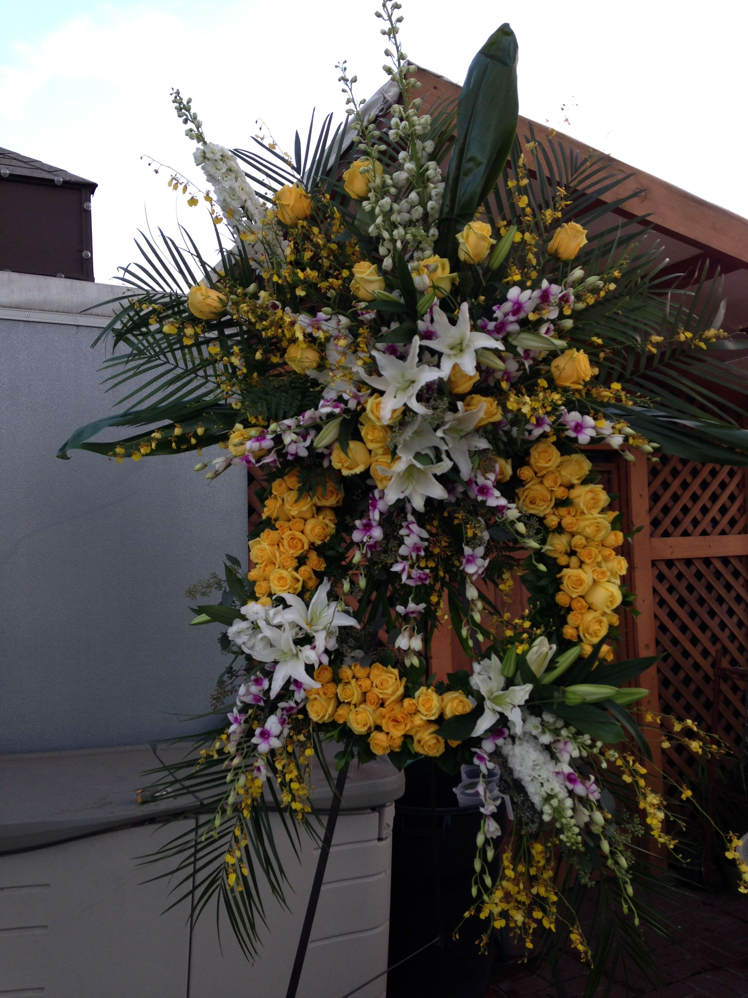 Large standing floral spray with yellow roses, white lilies, and orchids