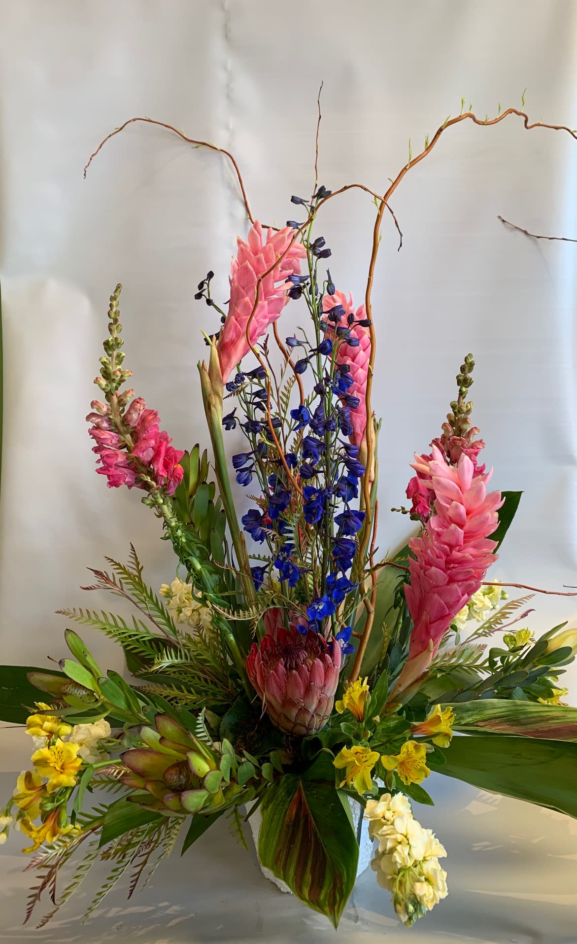 Tall tropical arrangement with pink and blue flowers in a vase