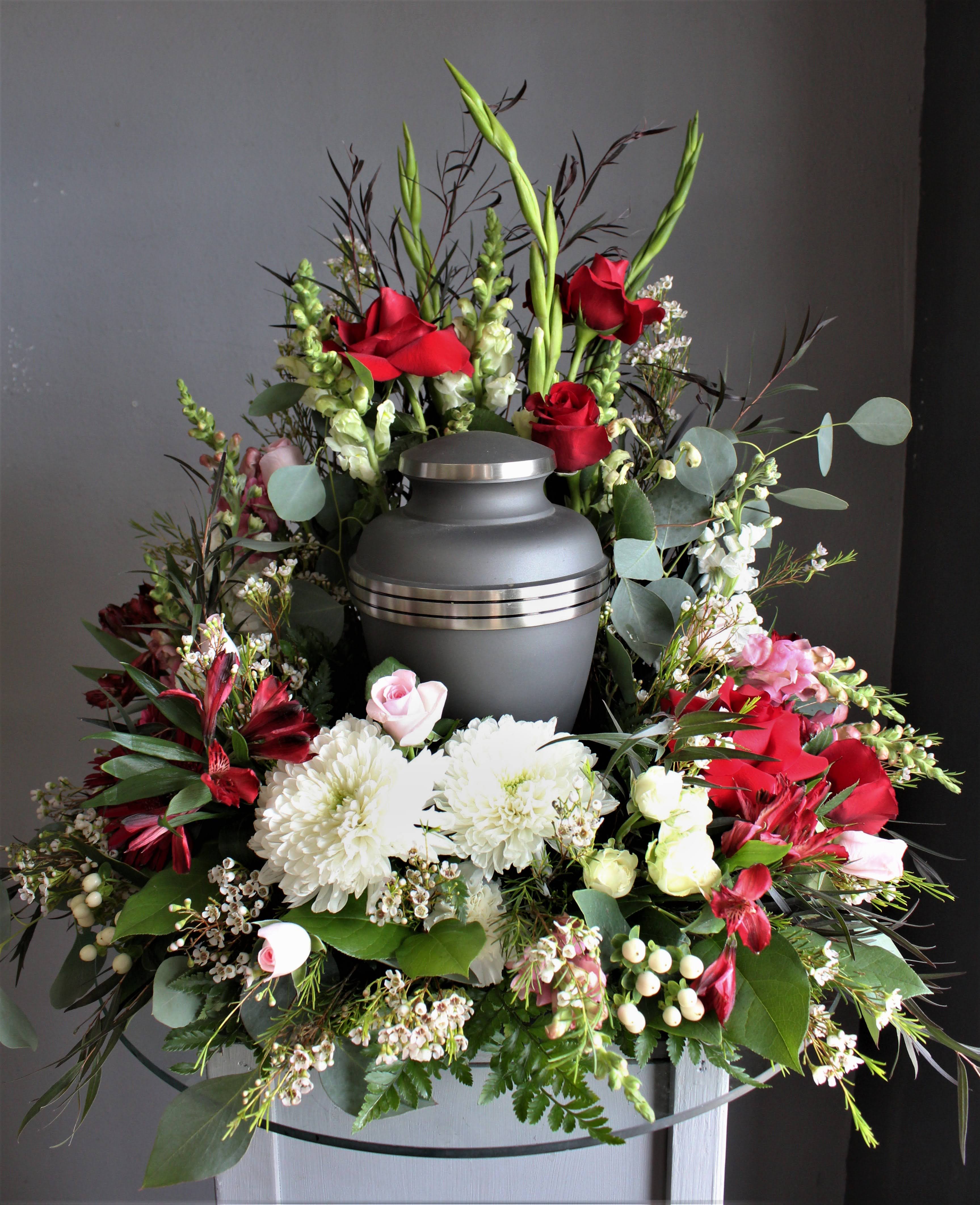 Funeral urn surrounded by red and white flowers in a wreath arrangement