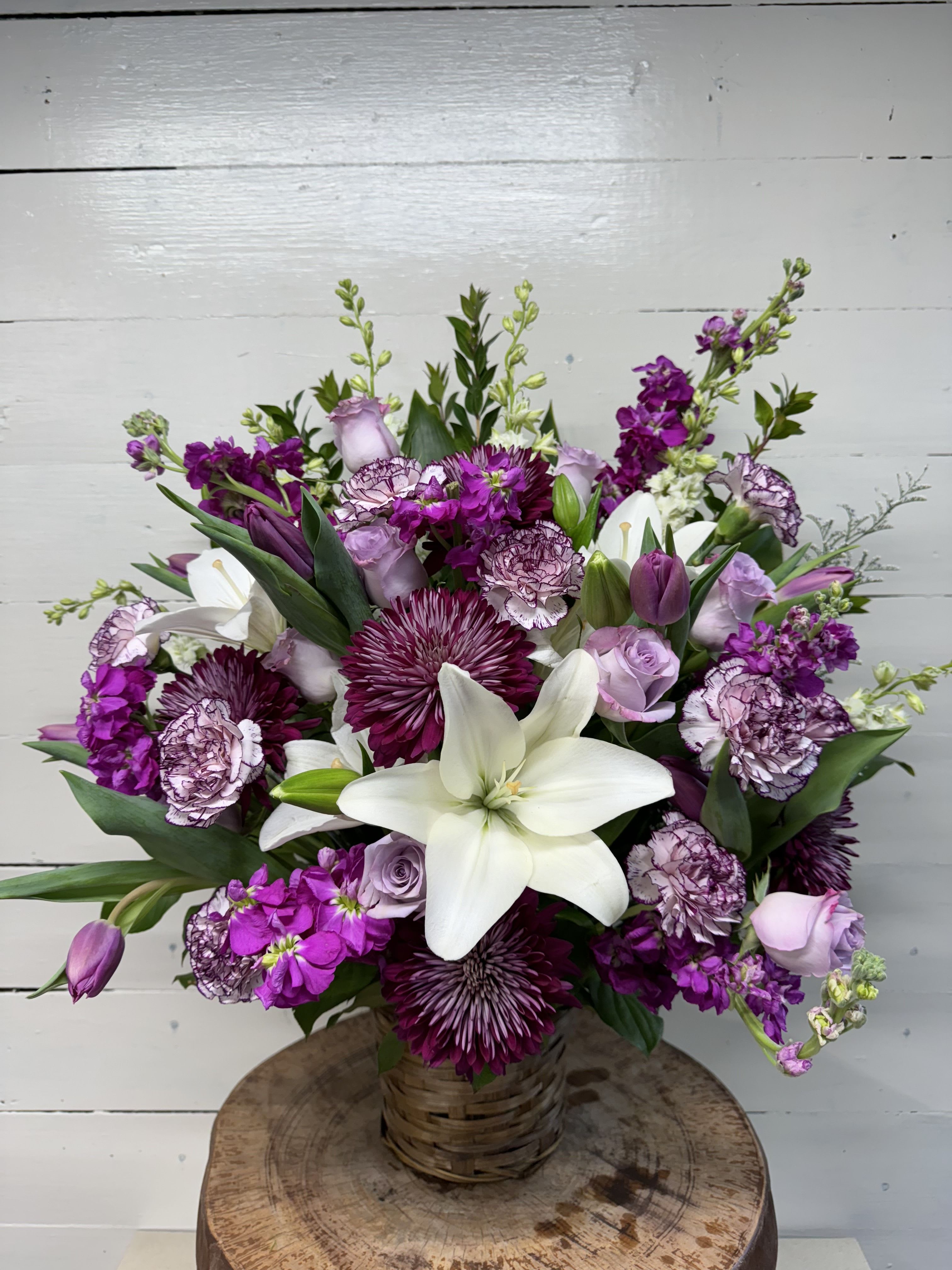 Purple and white mixed bouquet in a woven basket vase