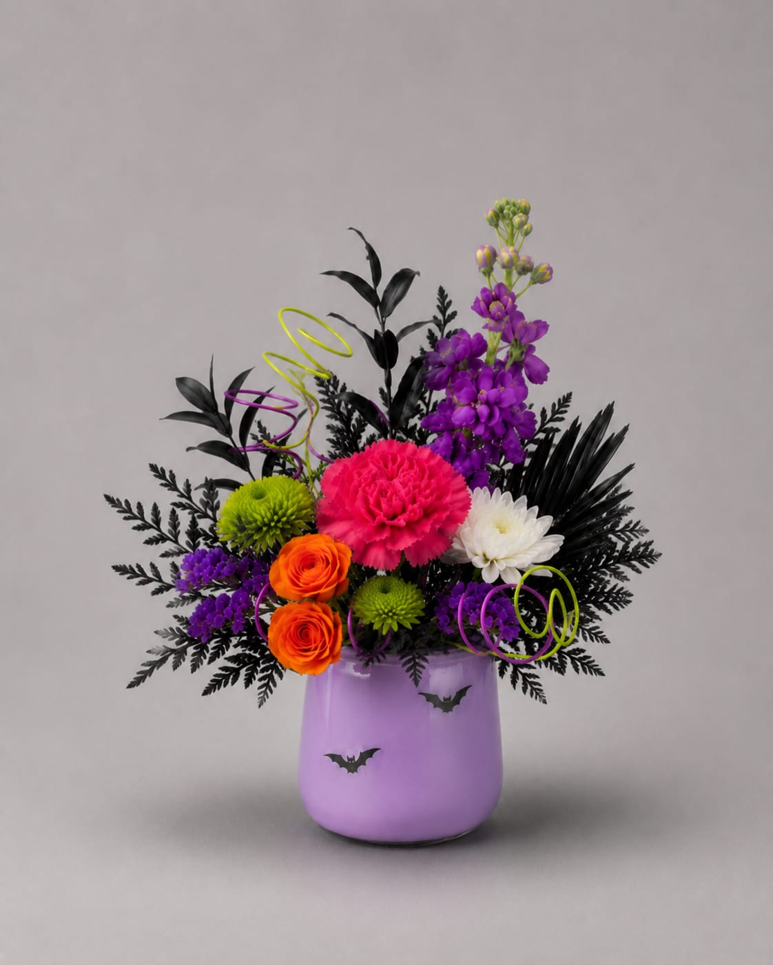 'Shake Señora' Bravo Bouquet - Your favorite cast and crew members will just die to receive the 'Shake Senora' Bravo Bouquet. It features a lavender vase adorned with bats in flight, vibrant blooms, and curls of ribbon and colorful wire to capture that after-life-of-the-party energy!  This arrangement was designed for our friends at the Penguin Project for their upcoming production of 'Beetlejuice Jr.'
