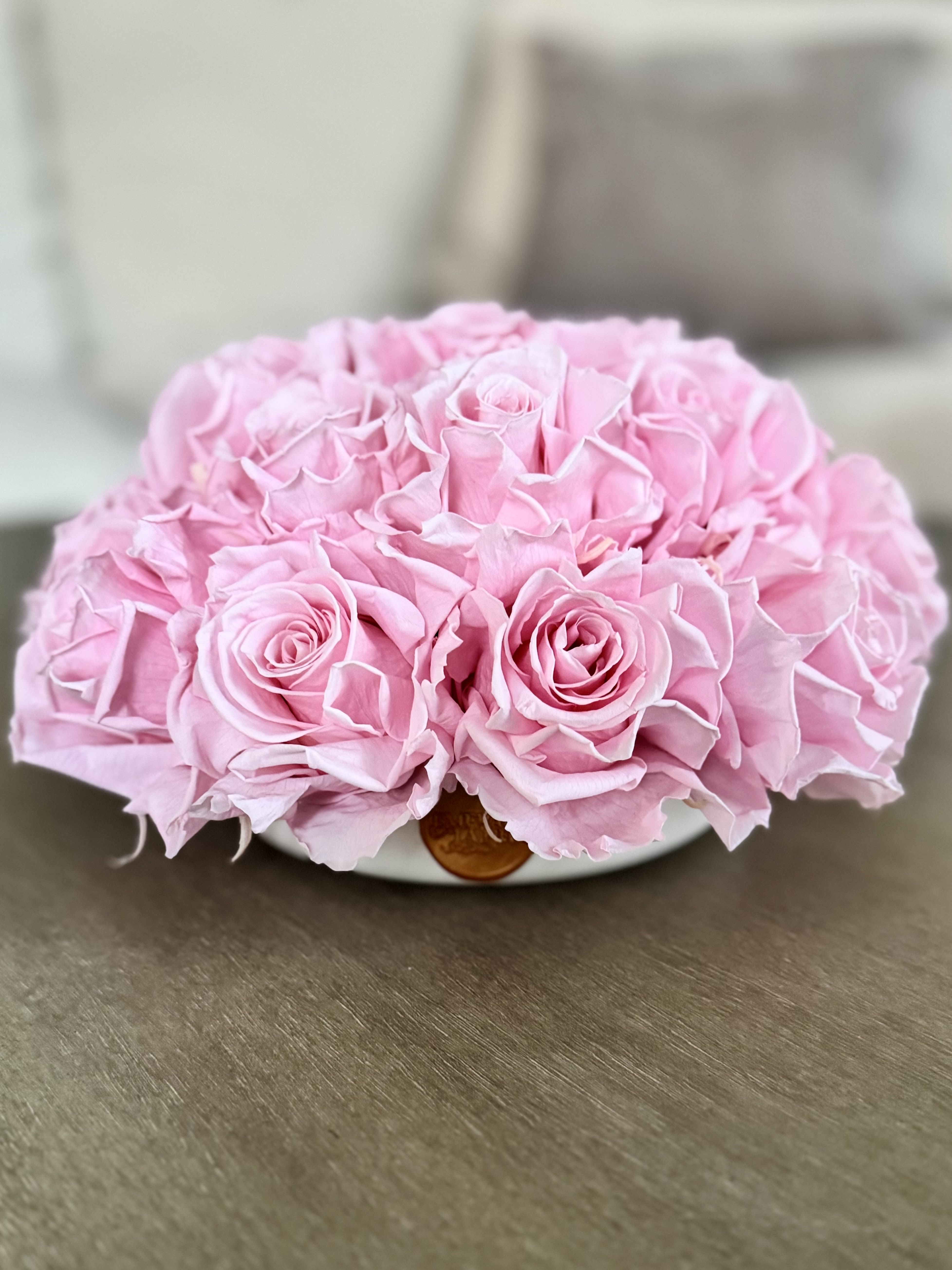 A low bouquet of pink roses in a shallow white container