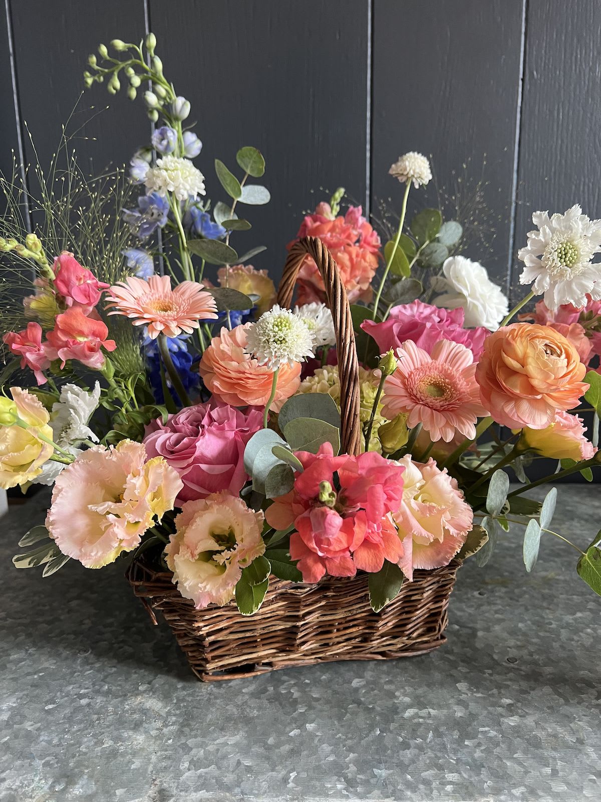 LARGE GARDEN BASKET  - Seasonal, colorful flowers and foliage artfully arranged in a rectangular woven basket.  Year round flowers that we typically stock: specialty rose, spray rose and garden rose, ranunculus, anemone, gerbera daisy, protea, lisianthus, chrysanthemum, larkspur, snapdragon, delphinium, stock, aster, dianthus, hypericum, feverfew, astrantia, leucodendron
