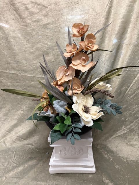 Tall floral arrangement with orchids and a white bloom in a pedestal vase