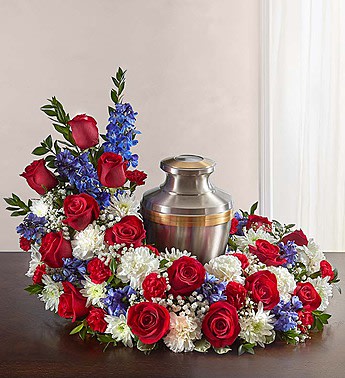 Red roses and white-blue flowers arranged around a metal urn
