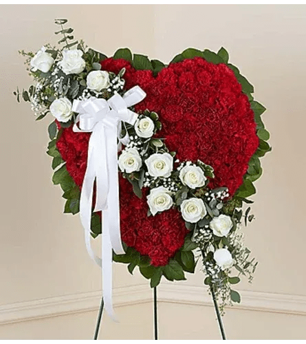 Bleeding Heart (red field) - This solid red heart standing spray, accented with a slash of beautiful white roses, is a timeless symbol of your love, sympathy and support. Florist arranged and hand delivered to a funeral home. Same day delivery available. Measures approximately 24"H x 24"L