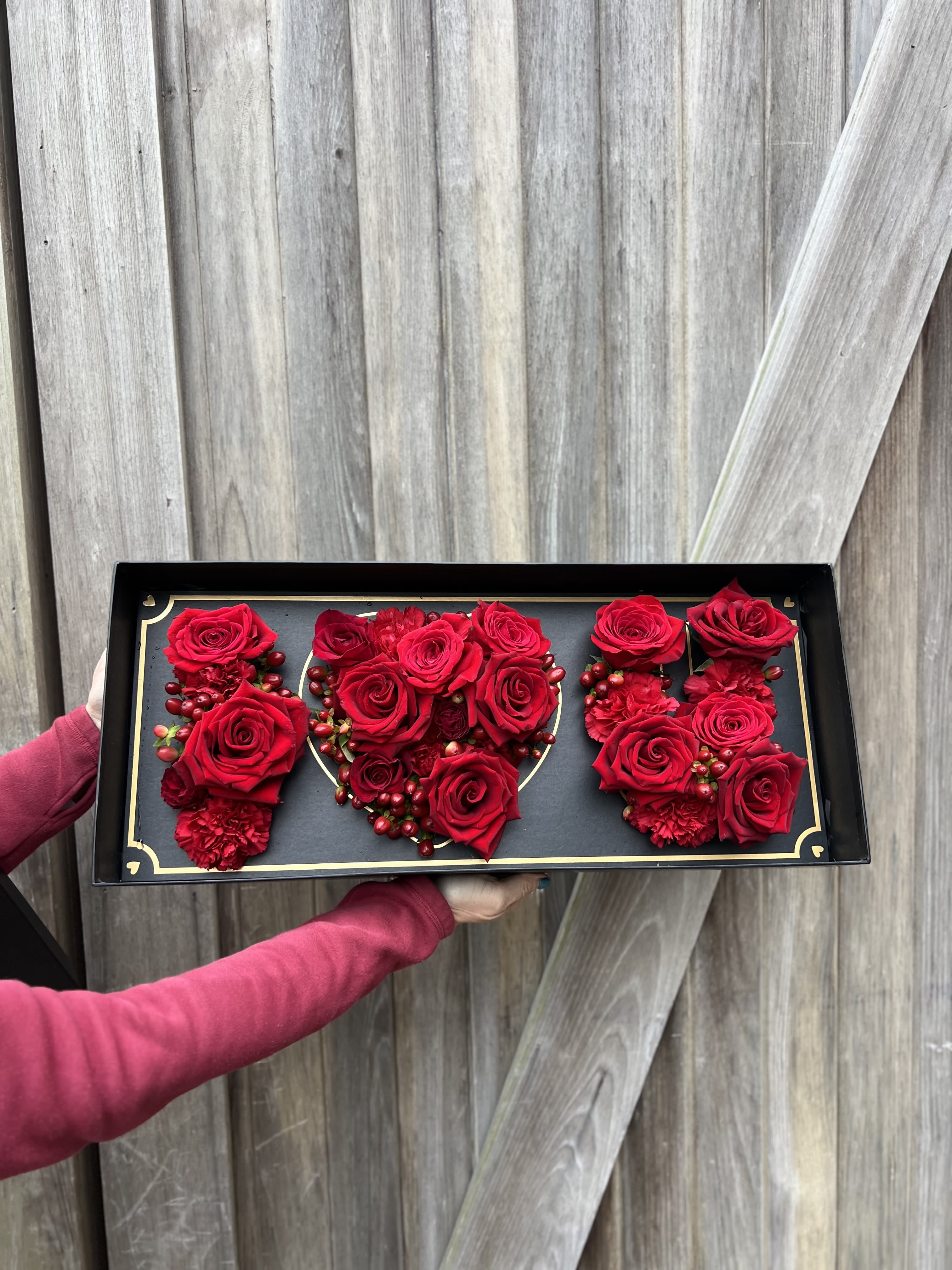 Red roses arranged in a black rectangular gift box