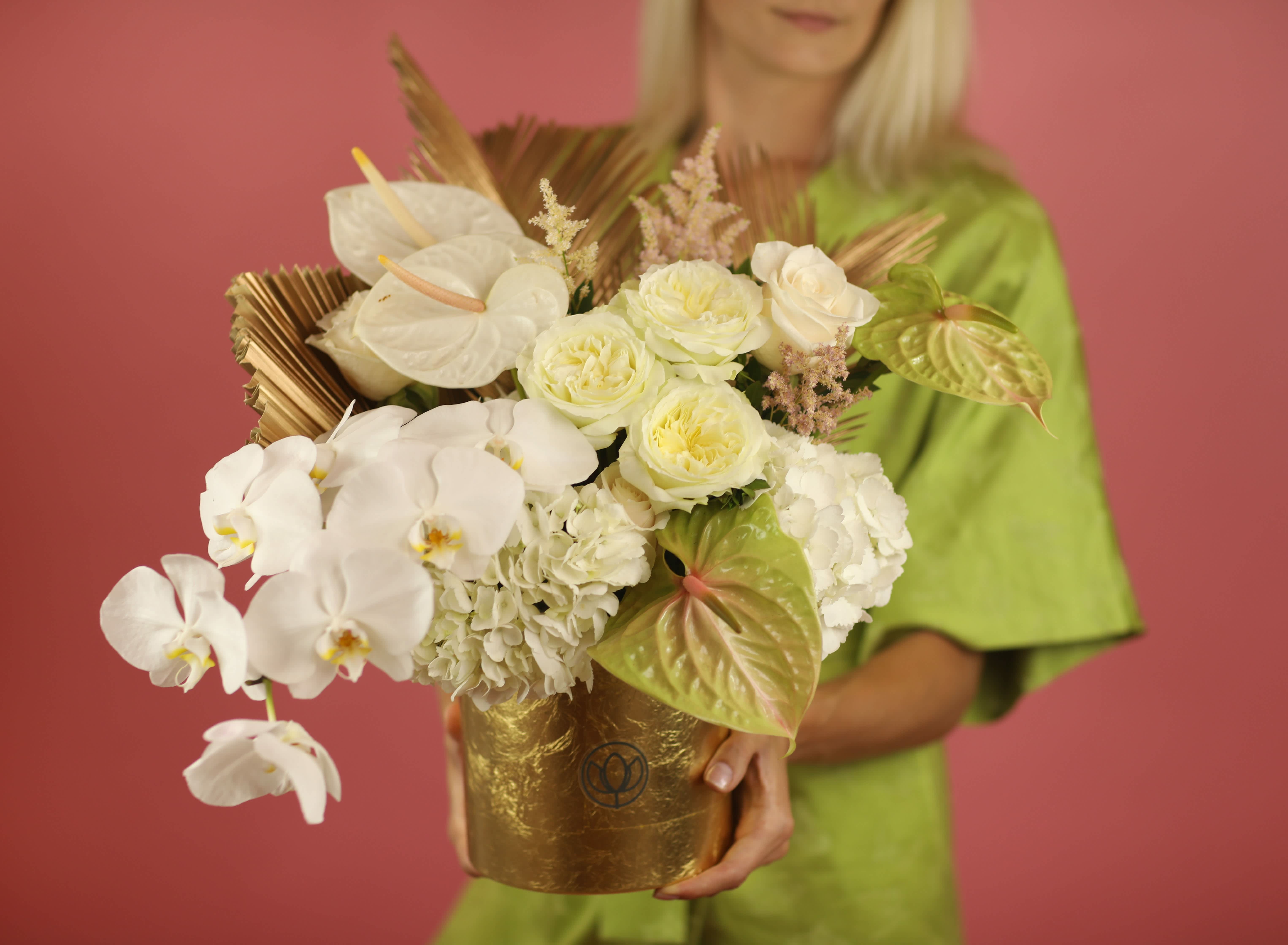 White orchid and rose arrangement in a gold container