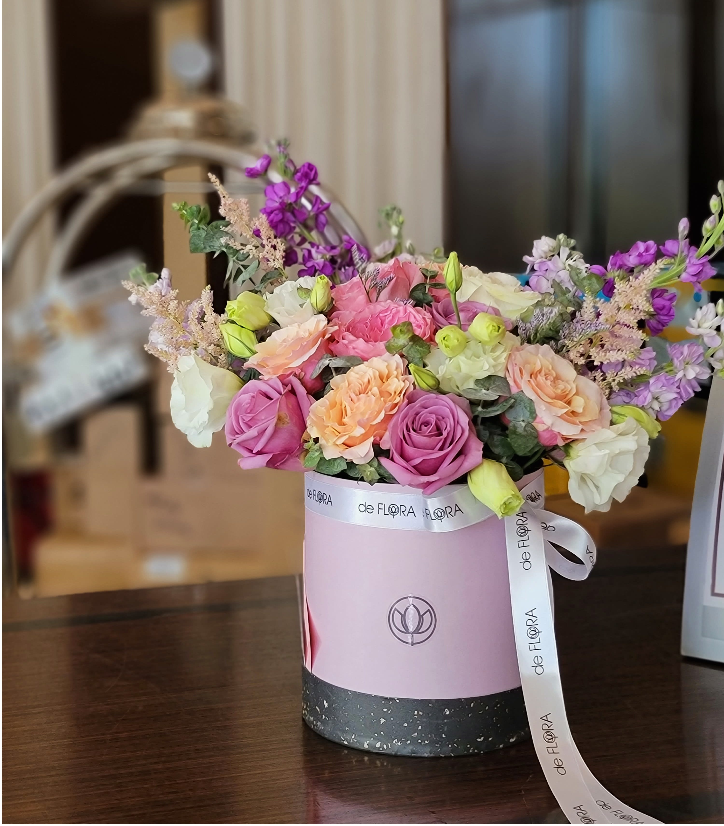 Pink and peach roses in a round gift box with a ribbon
