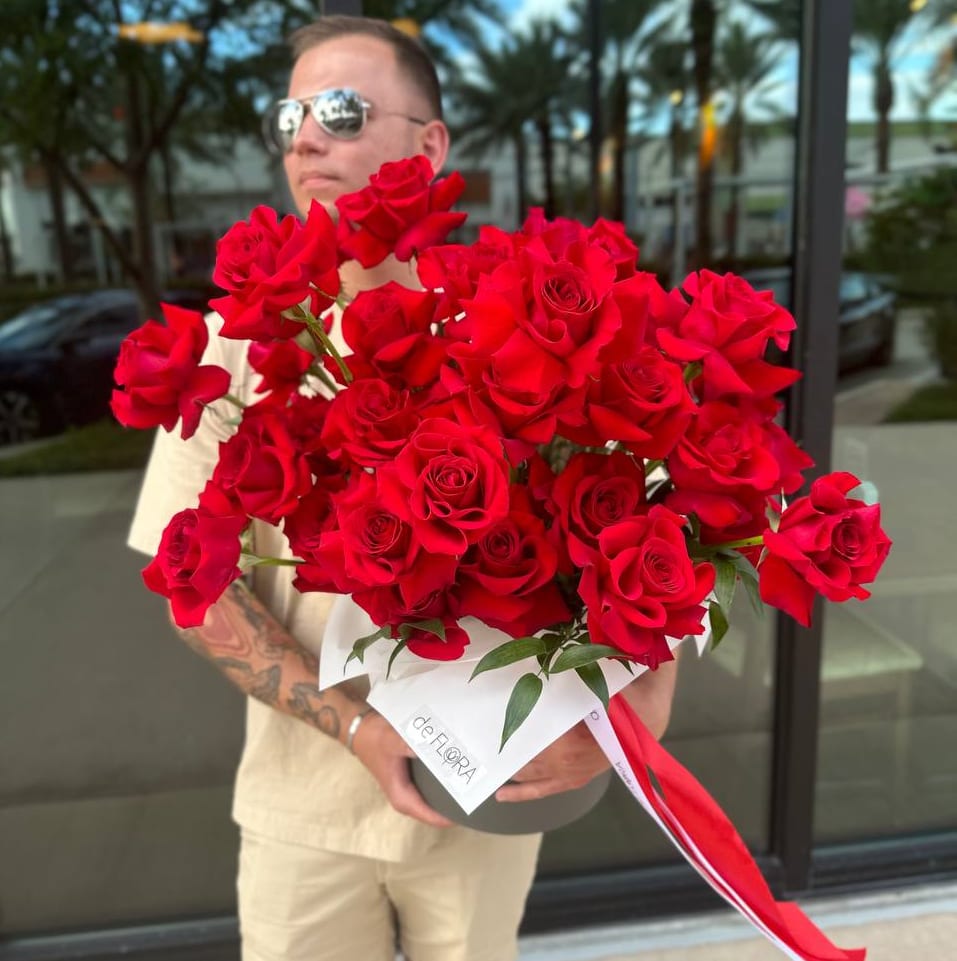 Large bouquet of red roses wrapped in white paper with a red ribbon