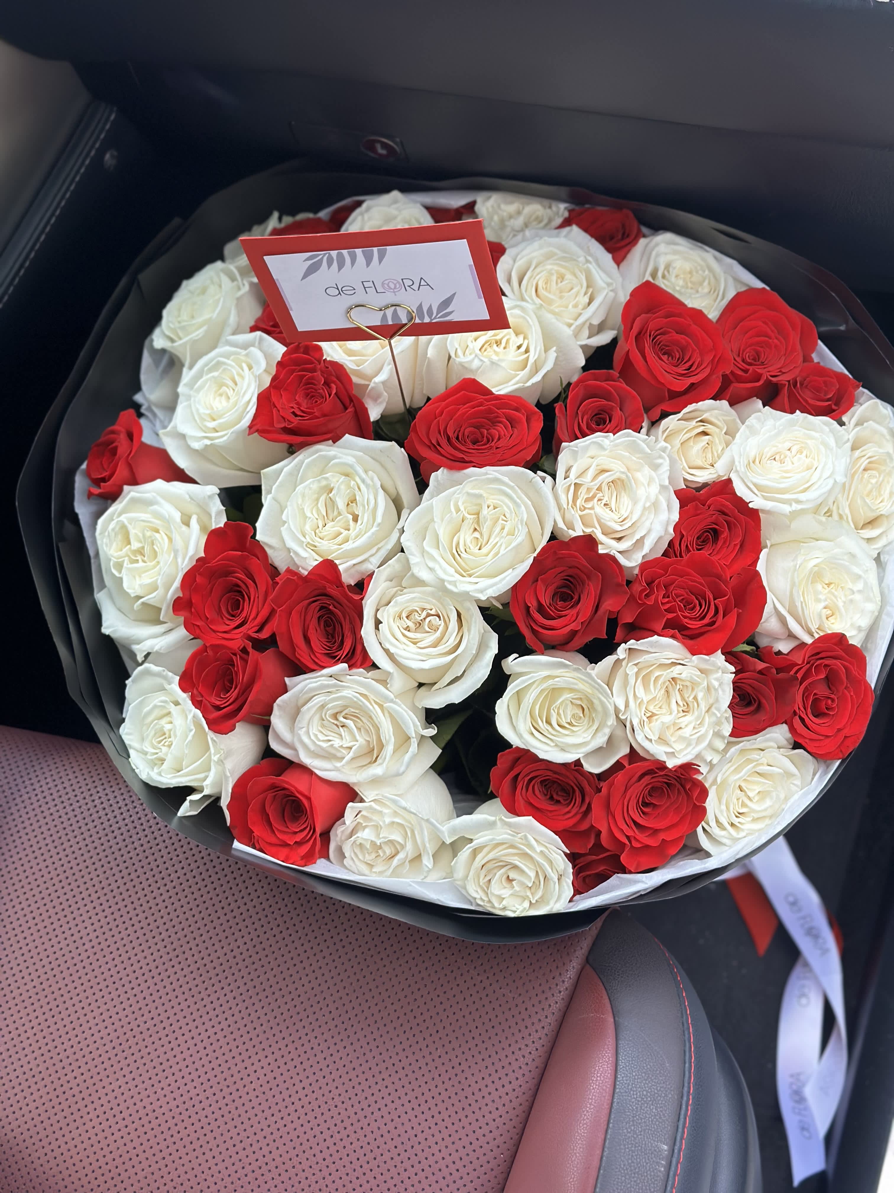 Round bouquet of red and white roses in black wrapping