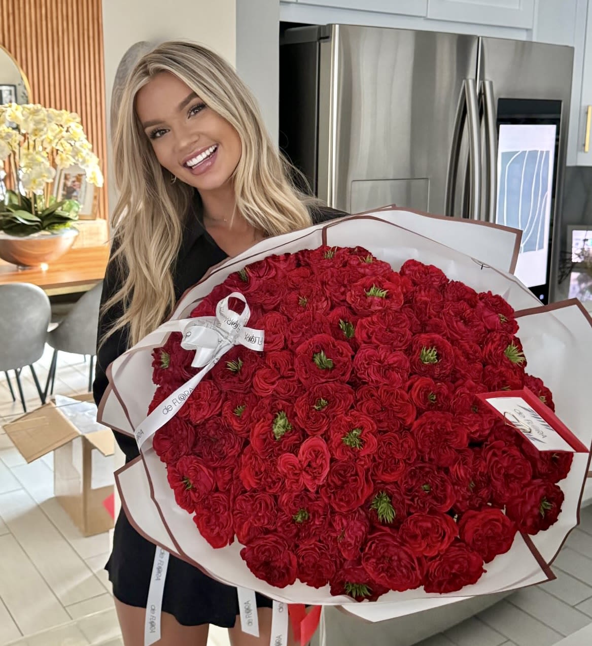 Woman holding a large bouquet of red roses wrapped in white paper