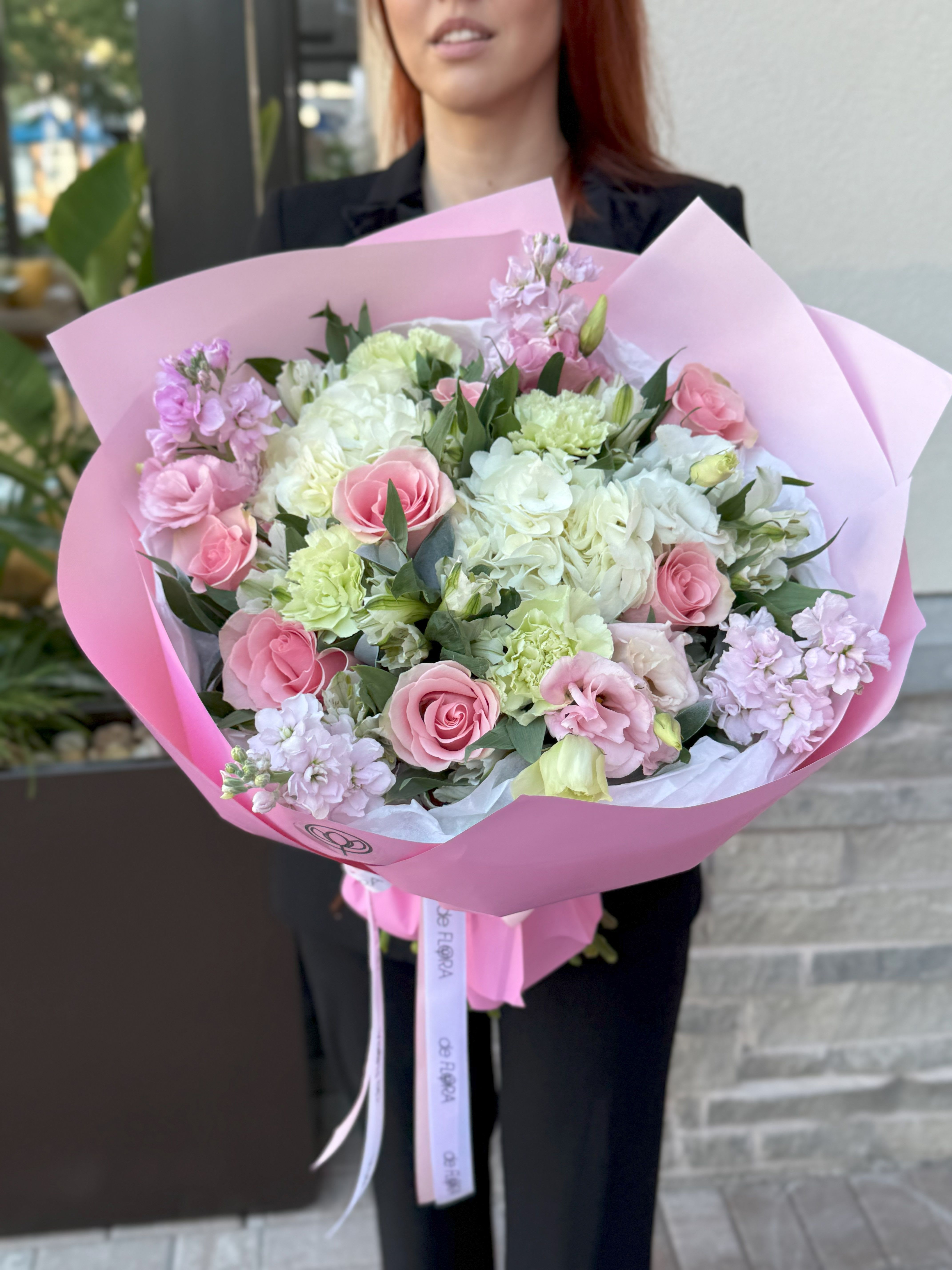 Pink and white bouquet with roses and carnations wrapped in pink paper