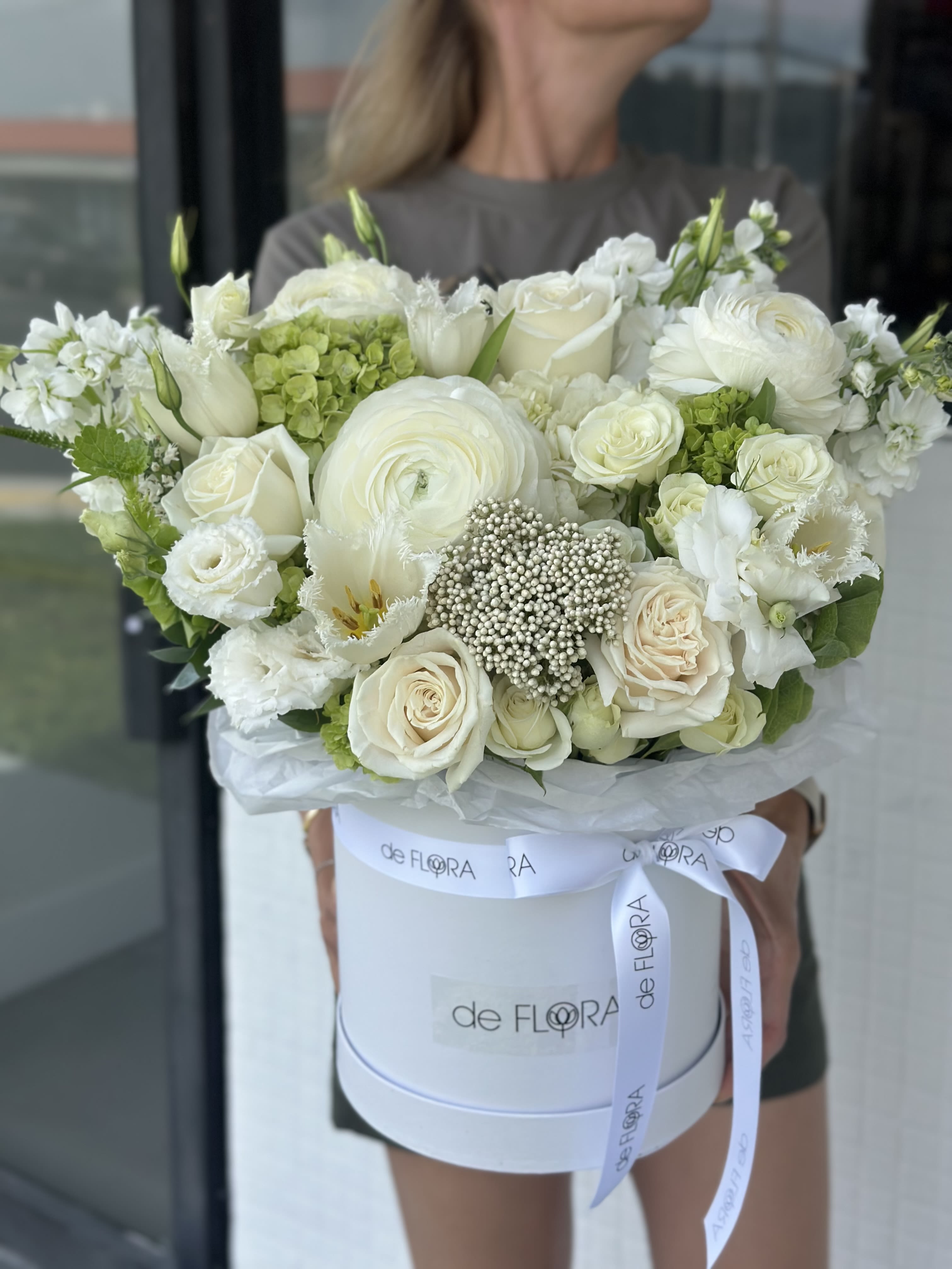 White rose and ranunculus bouquet in a round hat box with ribbon