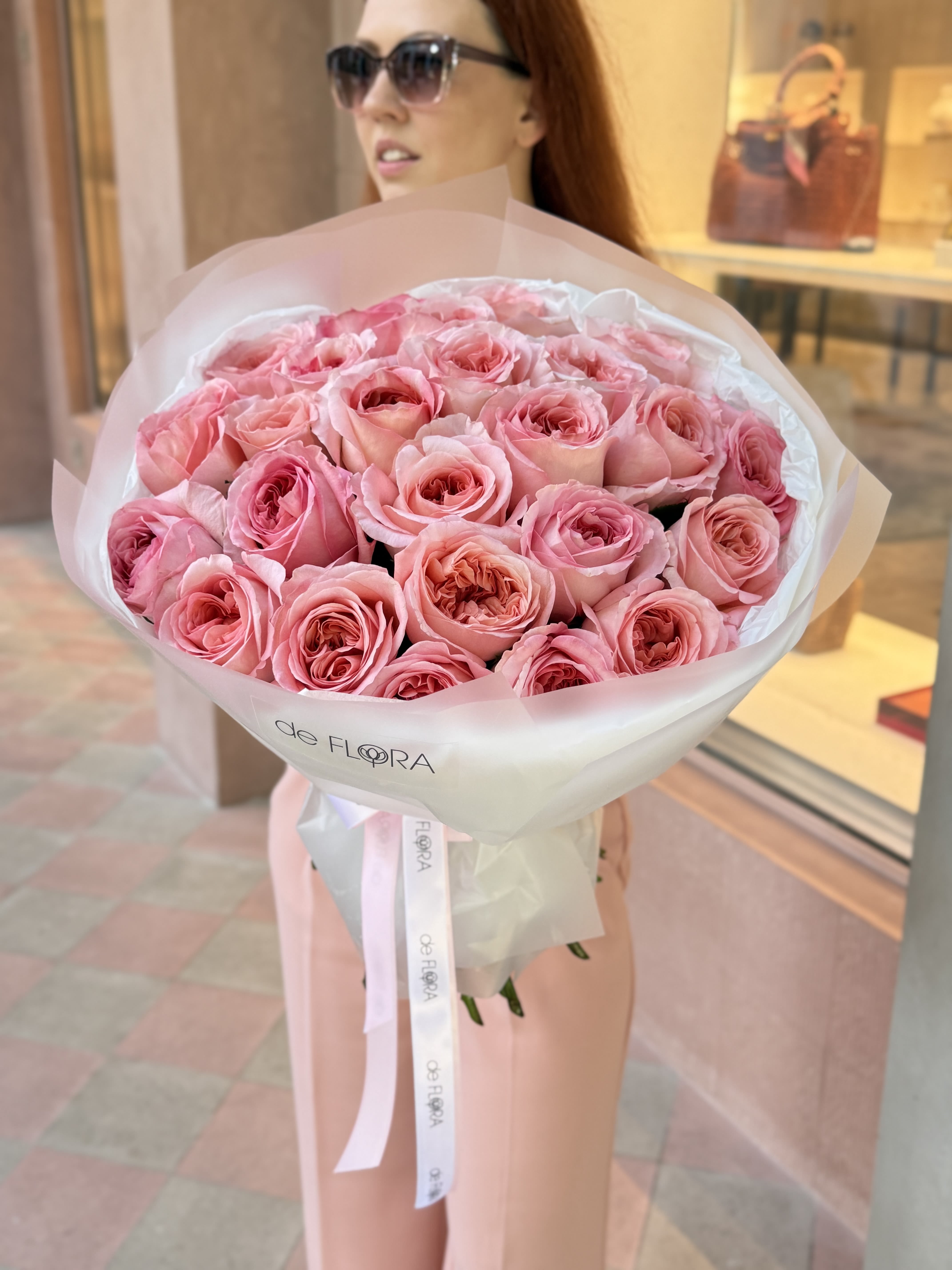 Large bouquet of pink roses wrapped in white paper with a ribbon