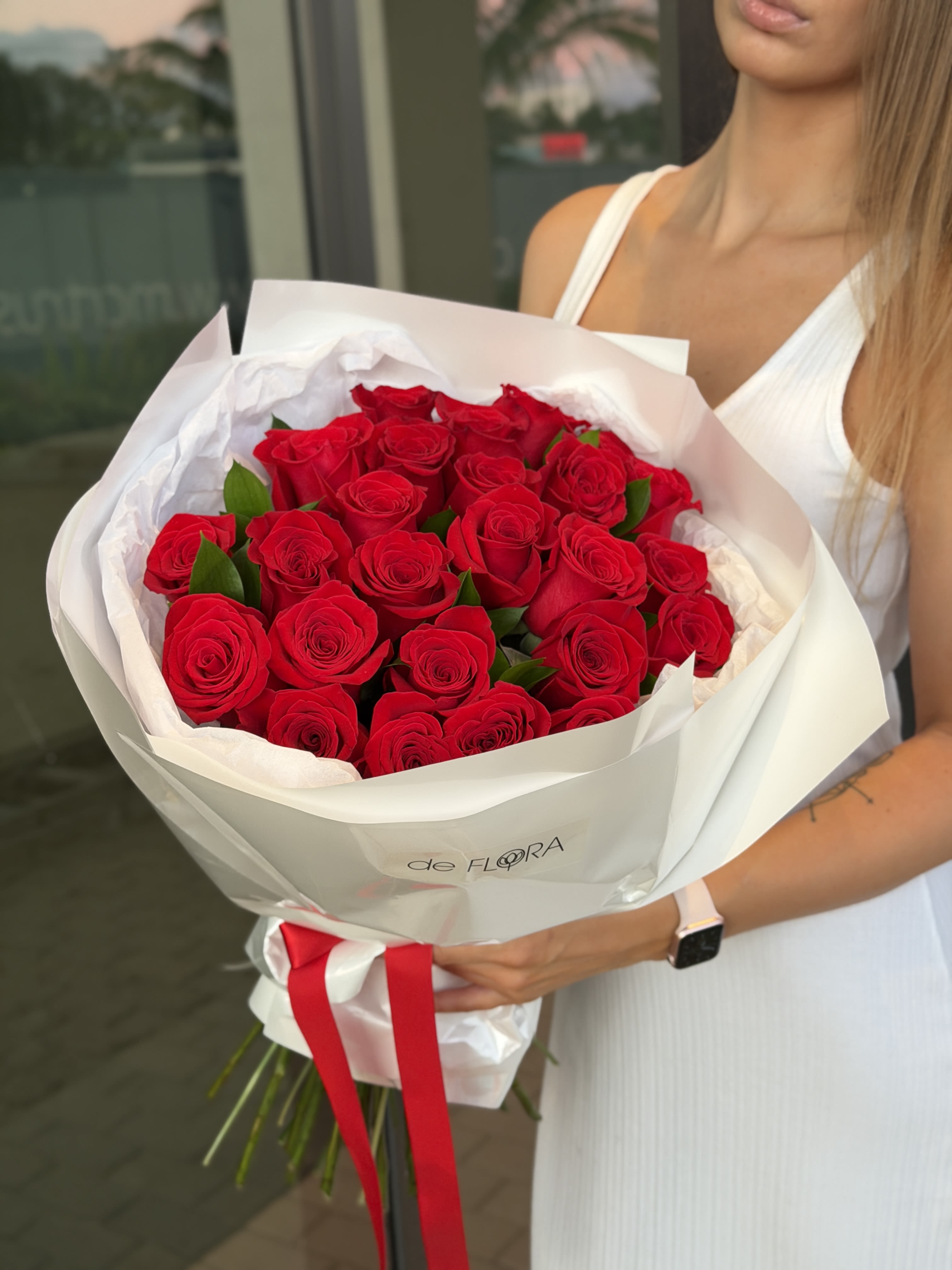 Bouquet of red roses wrapped in white paper with a red ribbon