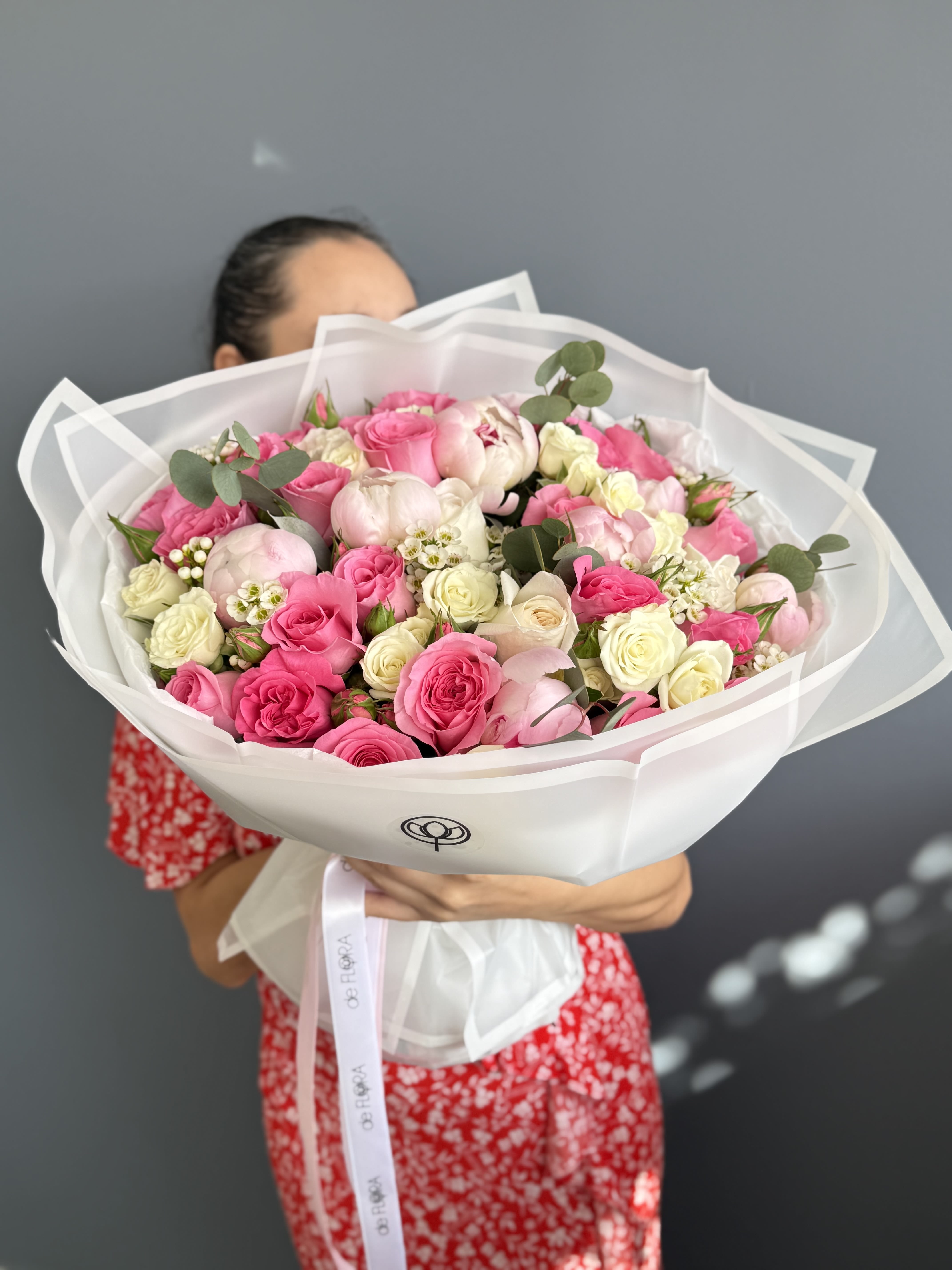 Large bouquet of pink and white roses wrapped in white paper