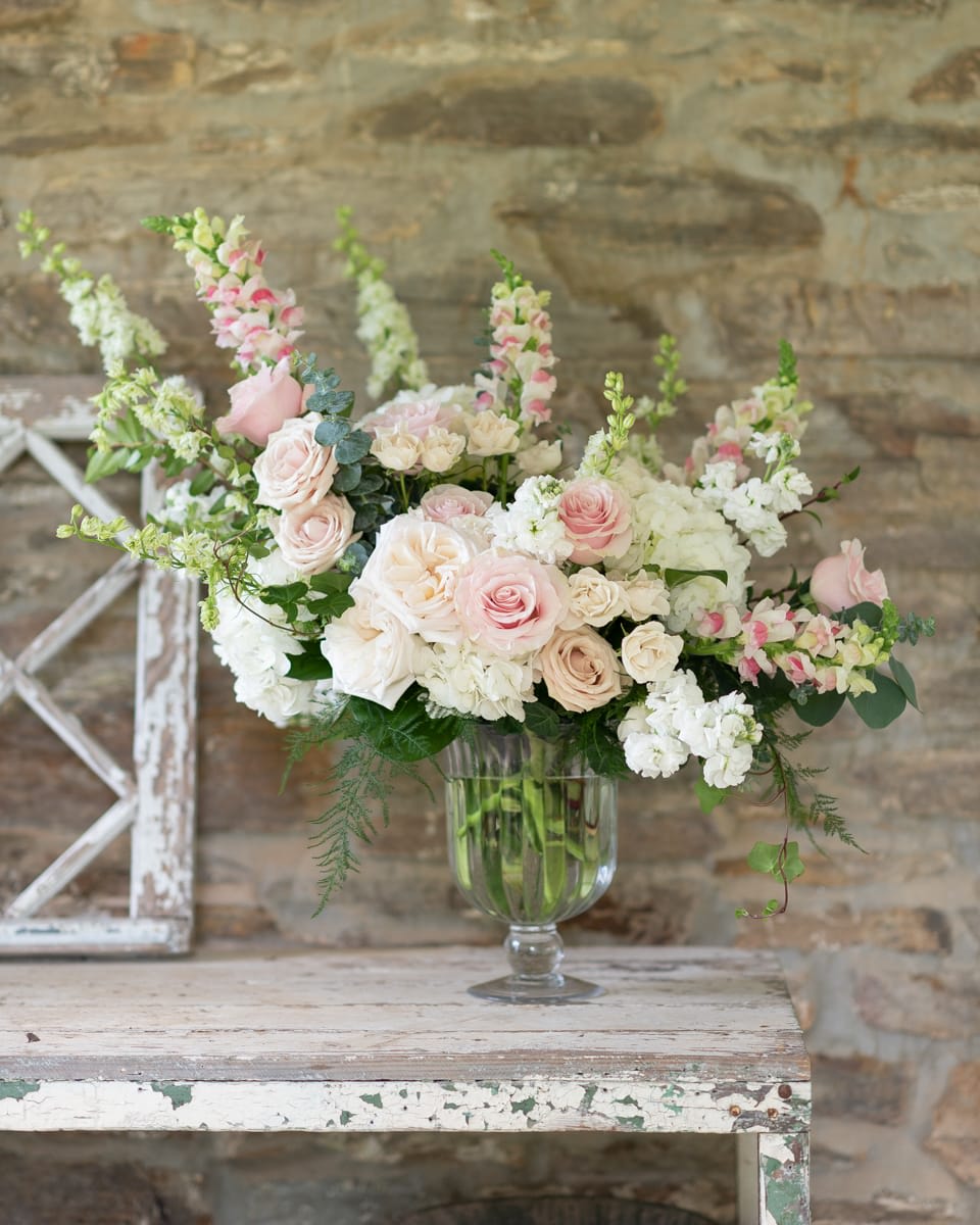 Blush and white rose arrangement in a clear glass vase