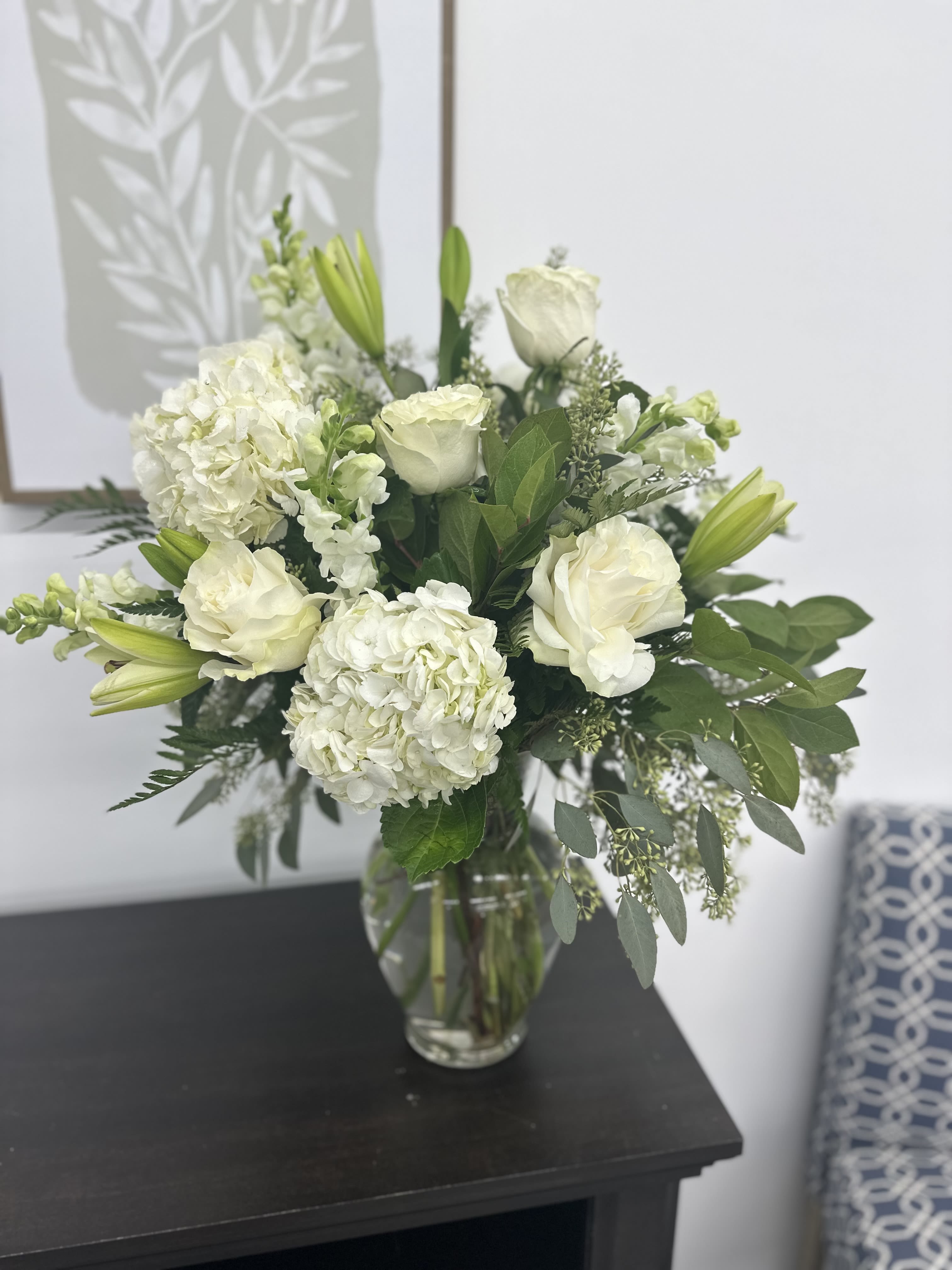Simple Bliss - This vase arrangement is ready to help you celebrate your special occasion. Full of white lilies, hydrangeas, roses, snapdragons, eucalyptus, and assorted greens this will surely brighten someones day. 