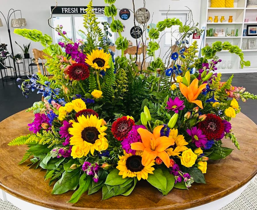 Dawn of Spring  - This colorful arrangement cradles the urn in a vibrant embrace. Colors and flowers may change based off of season and availability.