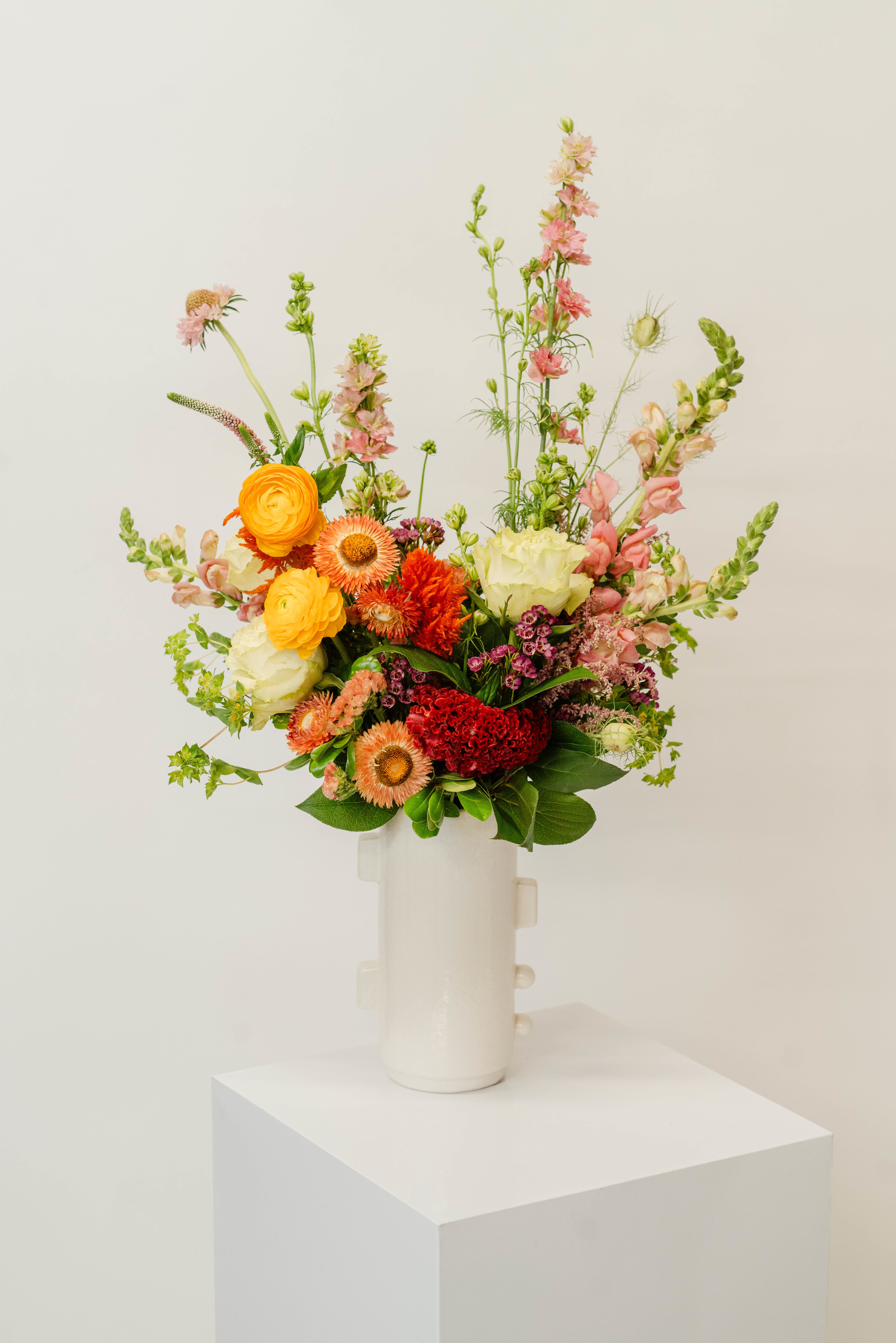 Colorful mixed bouquet in a white vase with tall pink stems