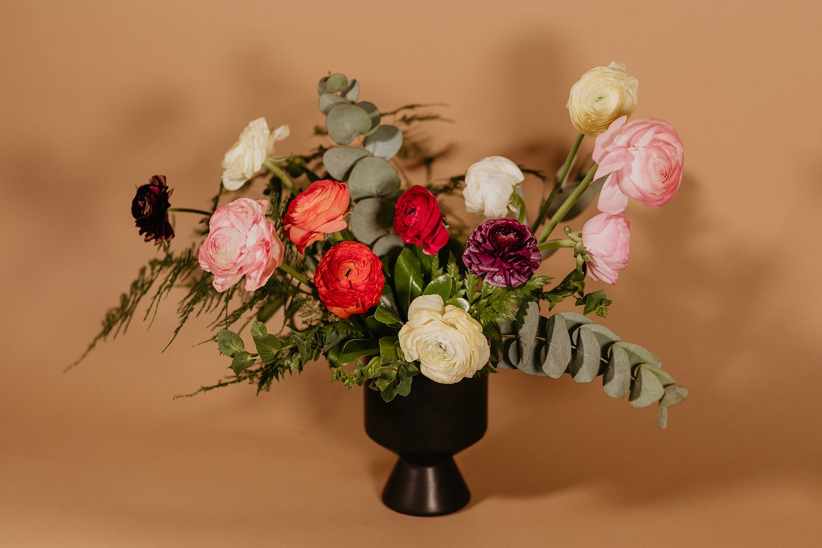 Mixed ranunculus bouquet in a black vase