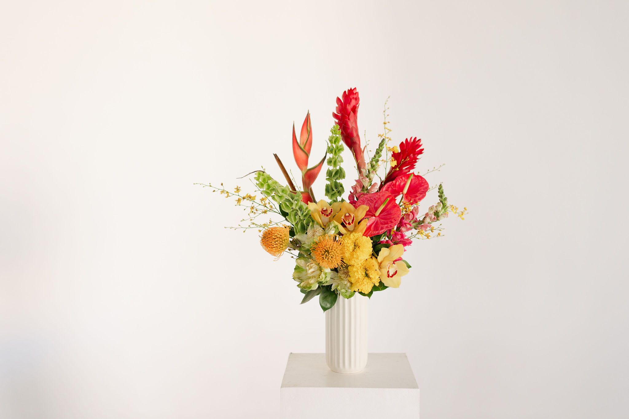 Deluxe Tropical Vase Arrangement - A bright, sunny, funky arrangement for your most unique, quirky and fun friend, mom, partner, or just yourself!   Featuring a blend of unique tropicals including orchids, helicona, ginger and protea, this is a really special, long-lasting arrangement which will truly bring the sunshine.  Occasionally, we may need to substitute individual blooms due to daily and seasonal availability so arrangements may not look exactly as pictures, but we will always substitute with similar flowers where possible.