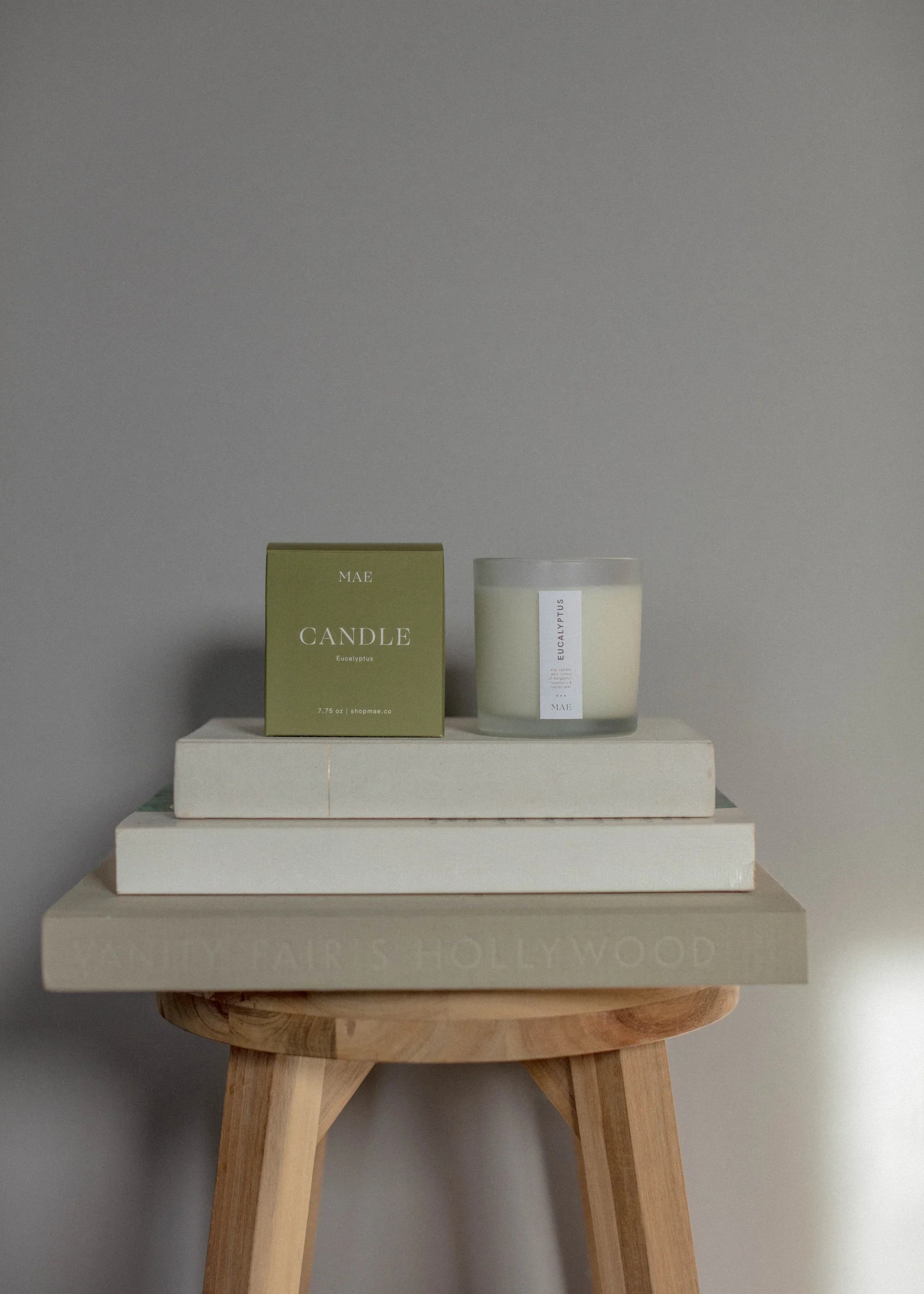 Eucalyptus candle in a glass jar beside its box on stacked books