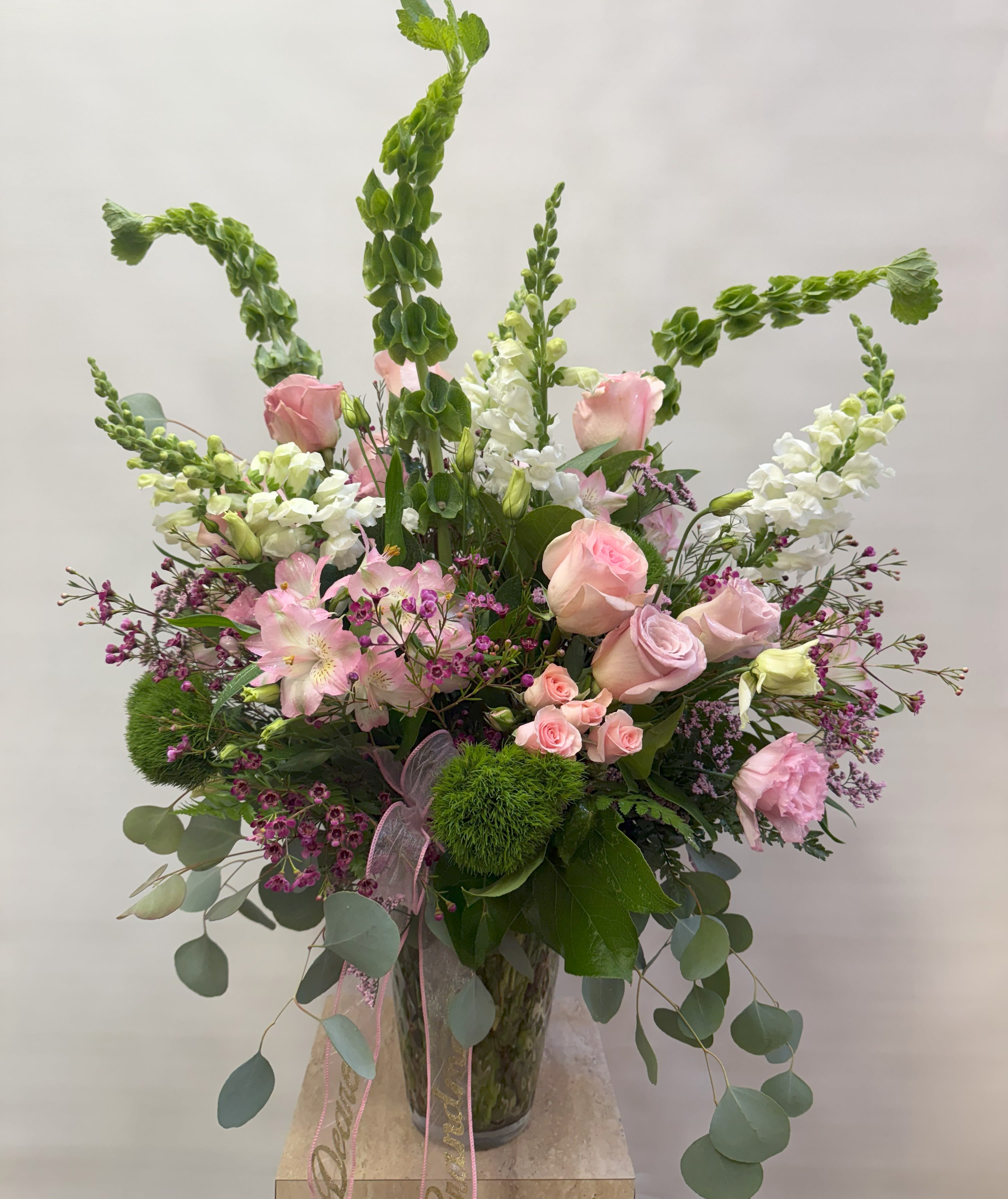 Tall bouquet of pink roses and white snapdragons in a glass vase