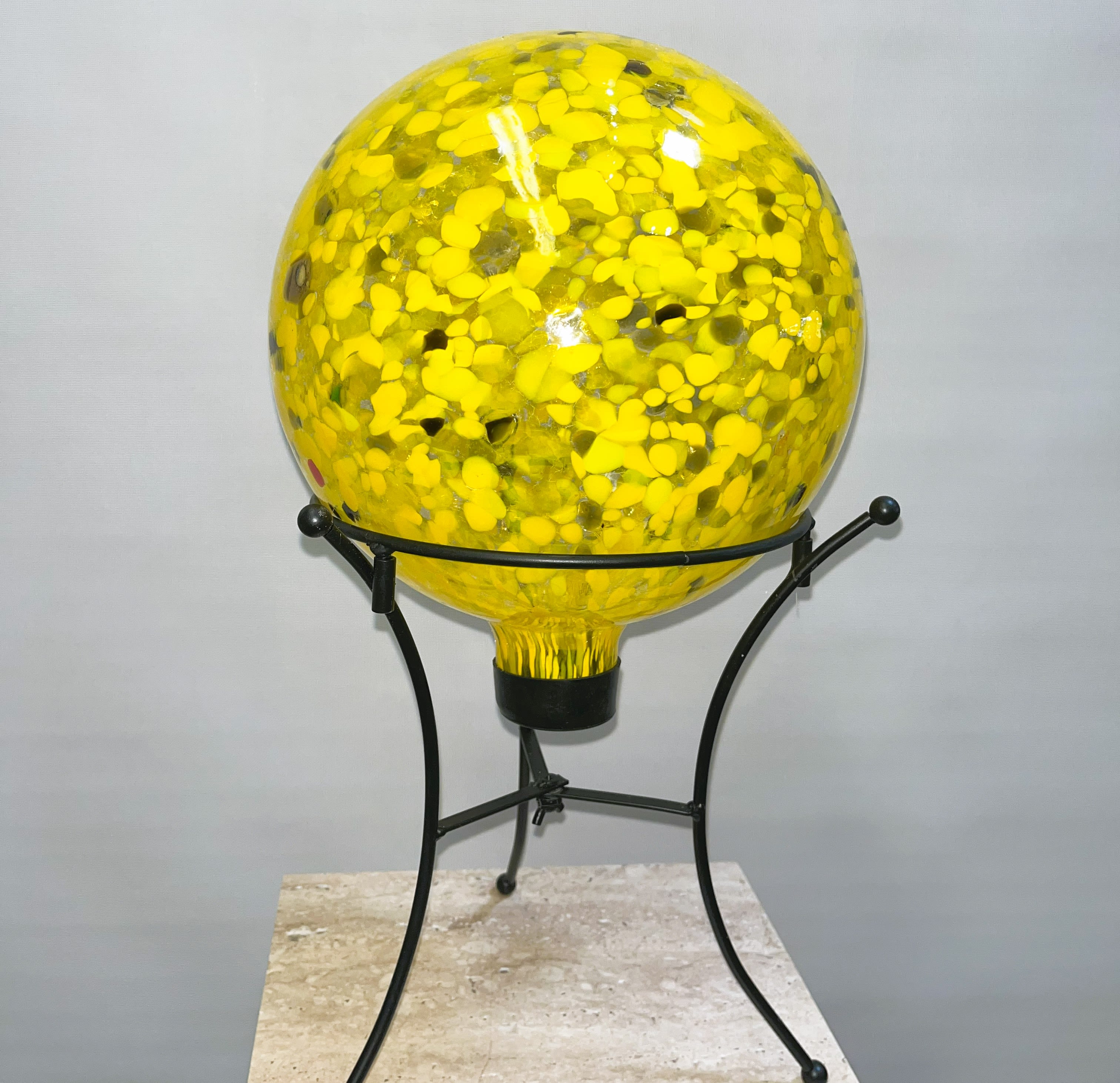 Yellow glass orb on a black metal stand