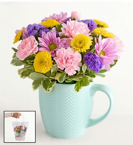Mixed pink, purple, and yellow flowers in a mint mug vase