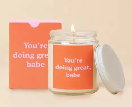 Lit candle in a glass jar beside an orange box