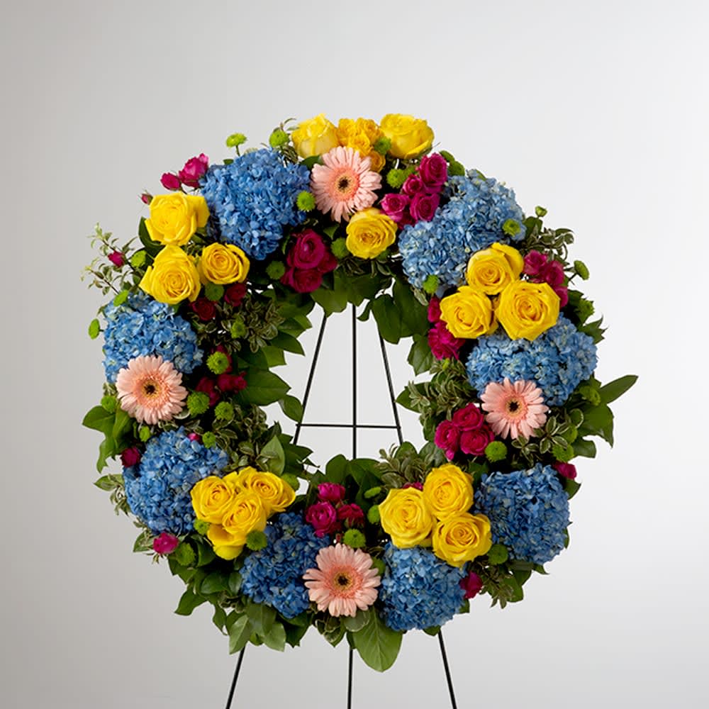 Colorful floral wreath with blue hydrangeas, yellow roses, pink gerberas, and magenta spray roses