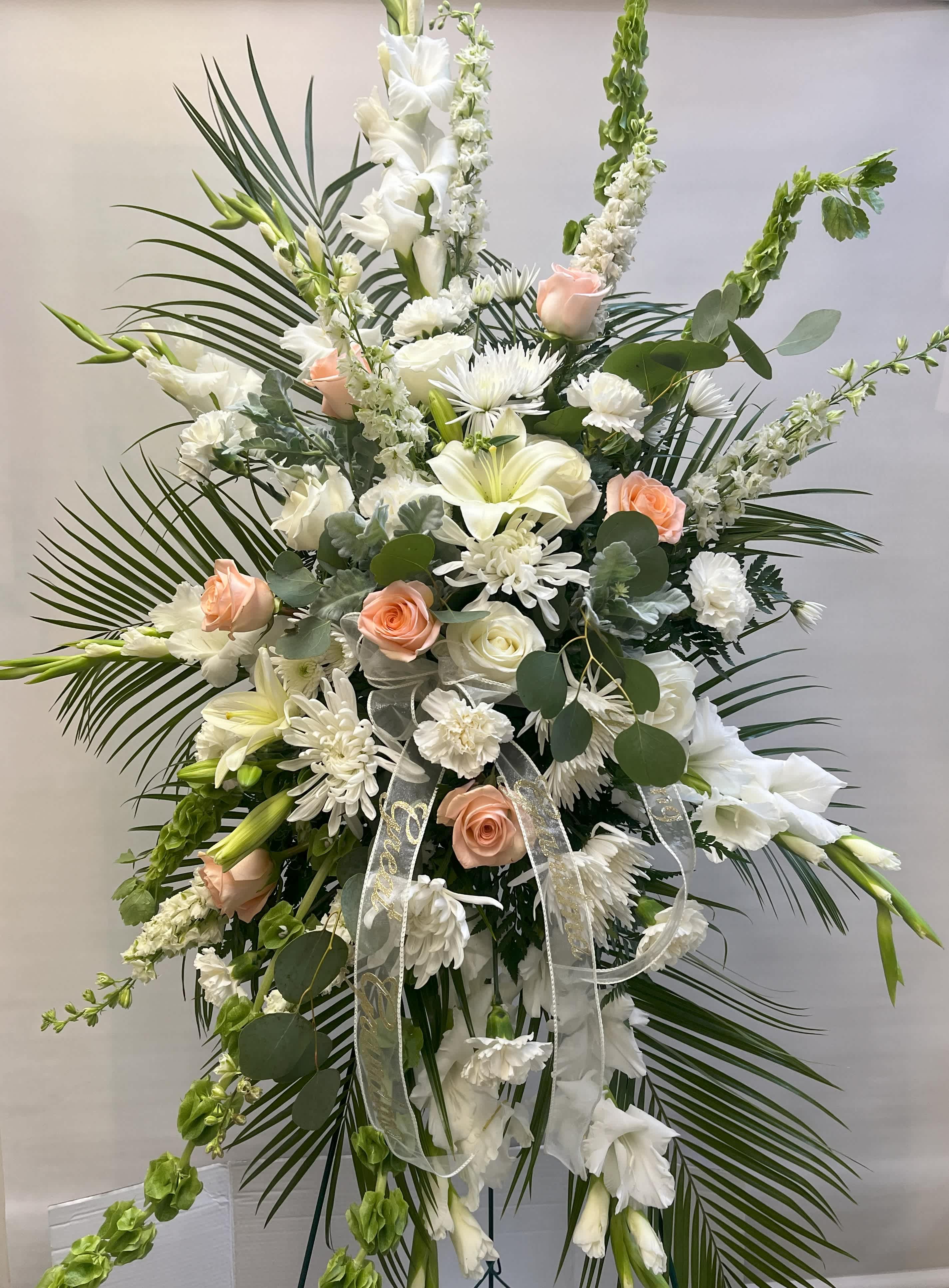 Tall white floral standing spray with peach roses and ribbon